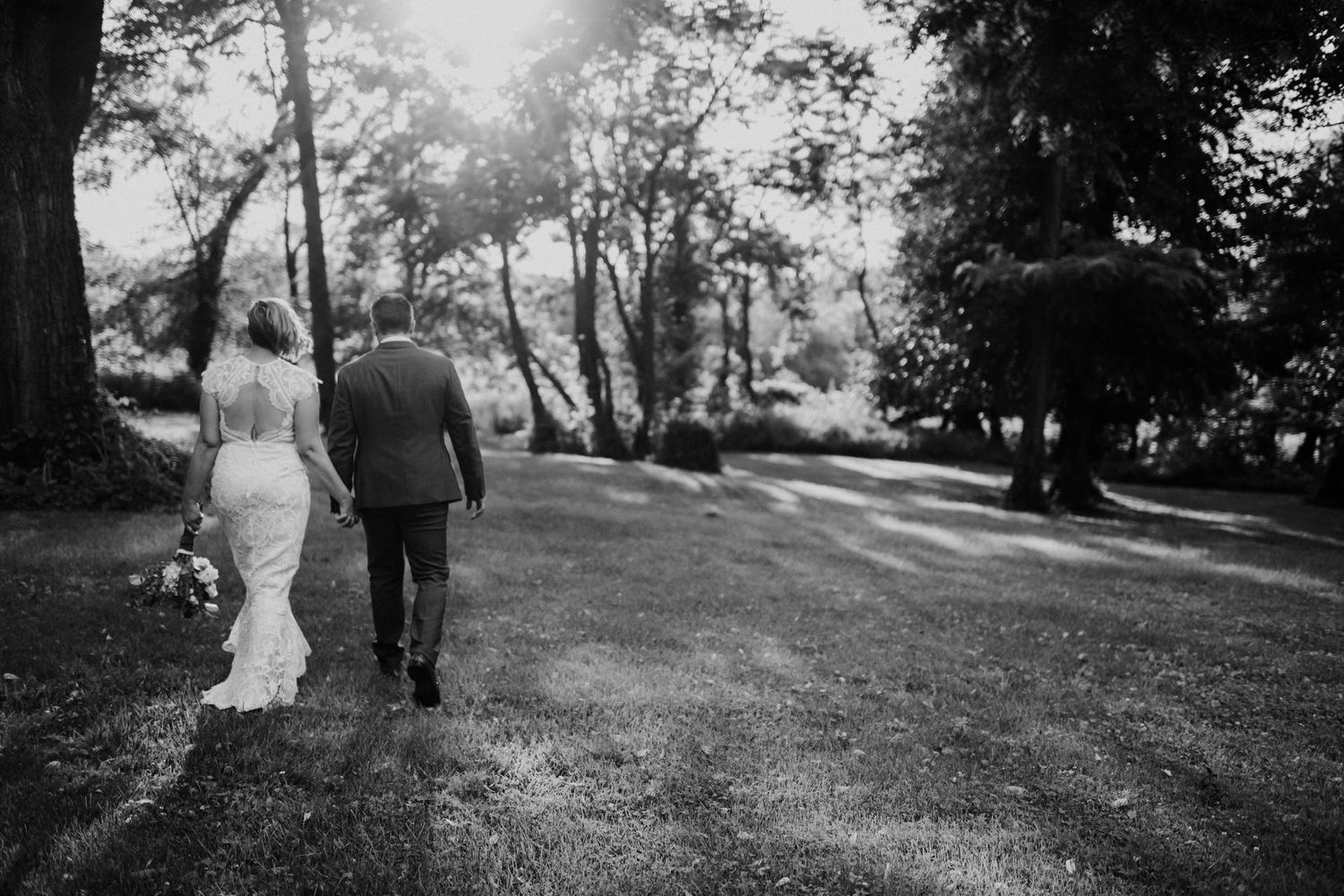 Couple walking together on sunlit garden path in black and white photography.