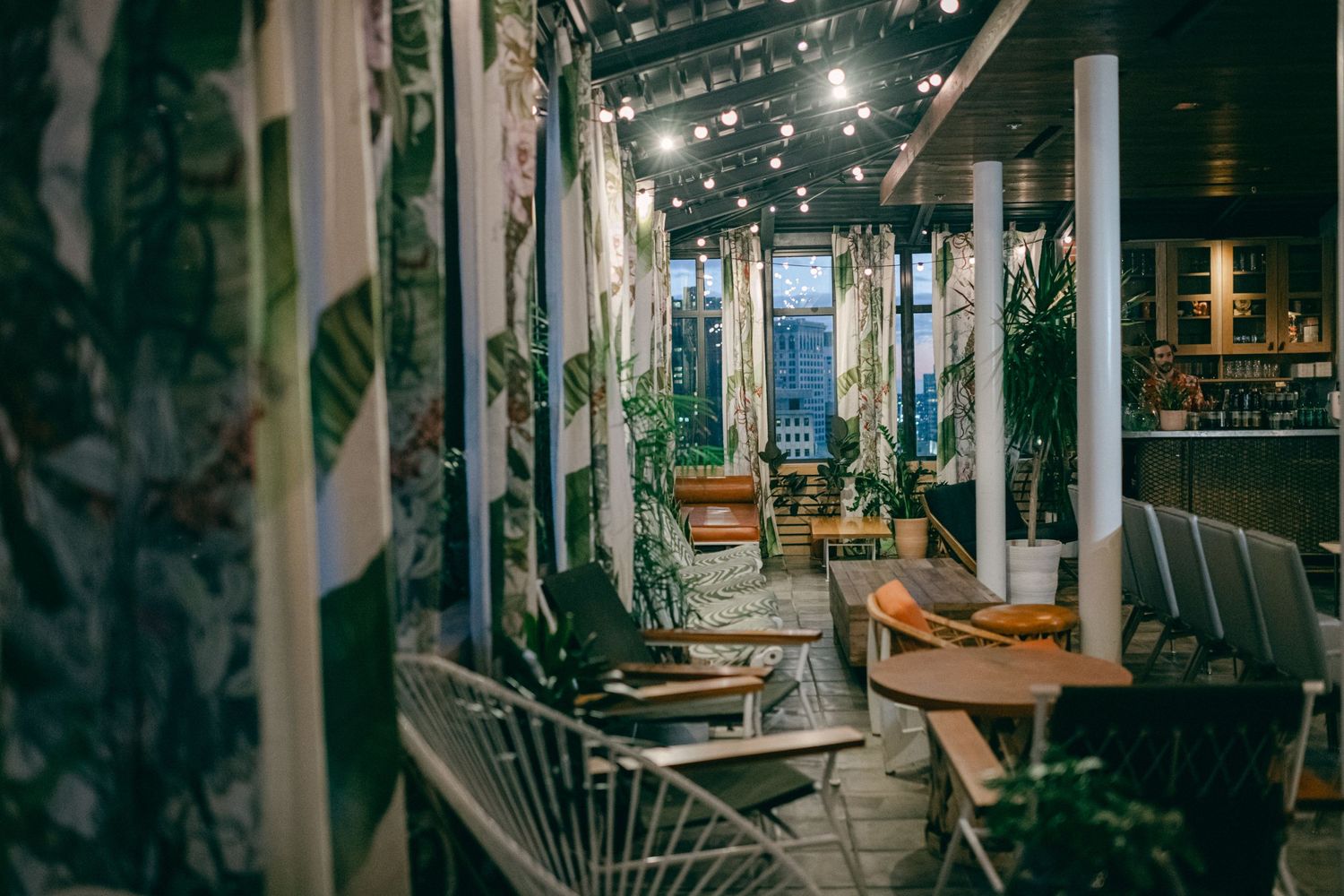 Modern restaurant interior with hanging plants, industrial lighting and wooden furniture.