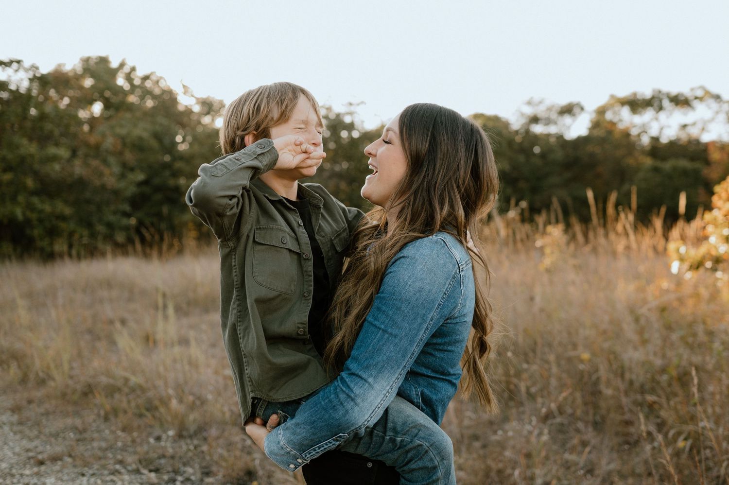Candid family photoshoot in rustic field during golden hour.