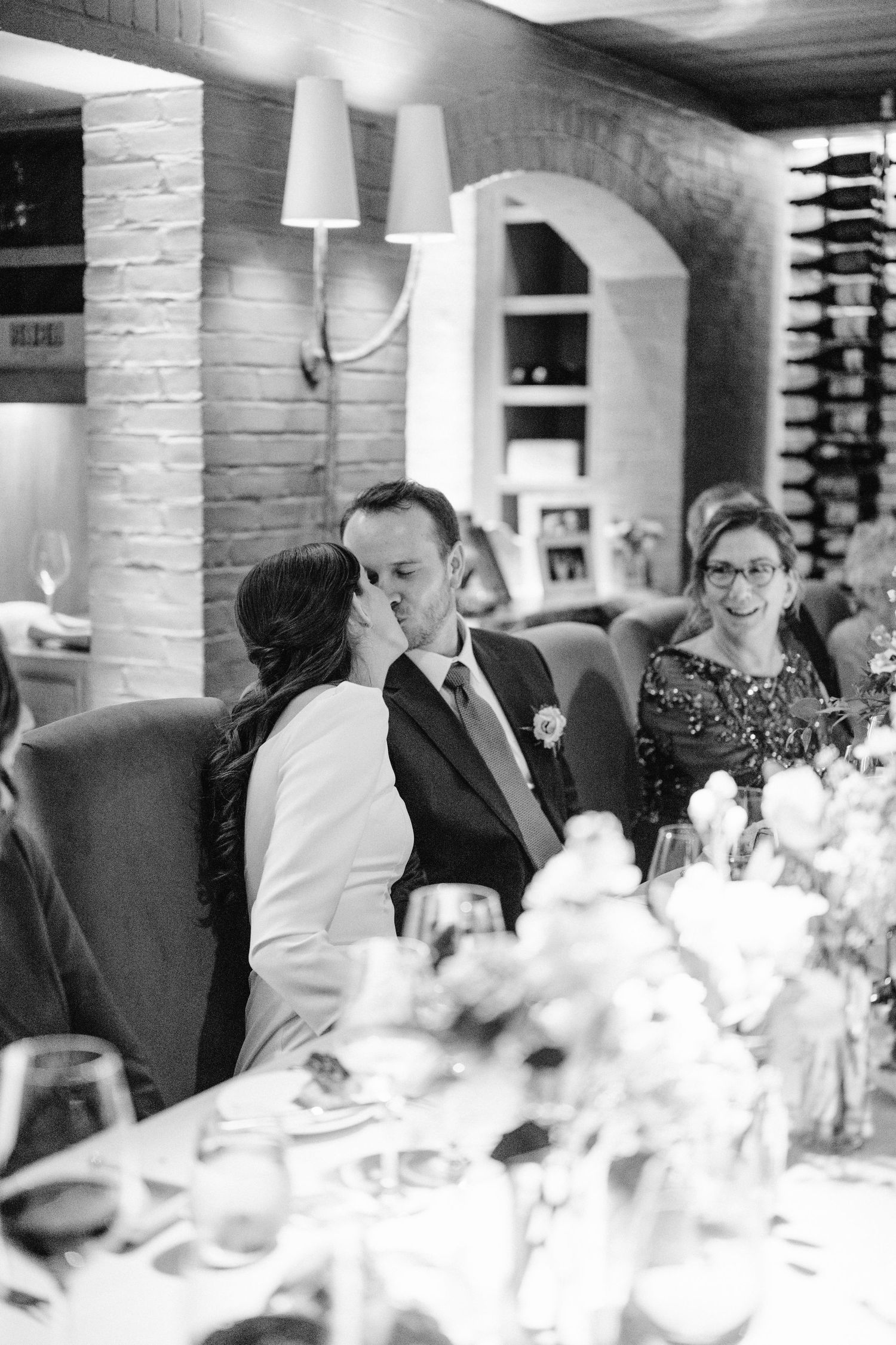 Black and white photo of an intimate wedding reception with white floral centerpieces.