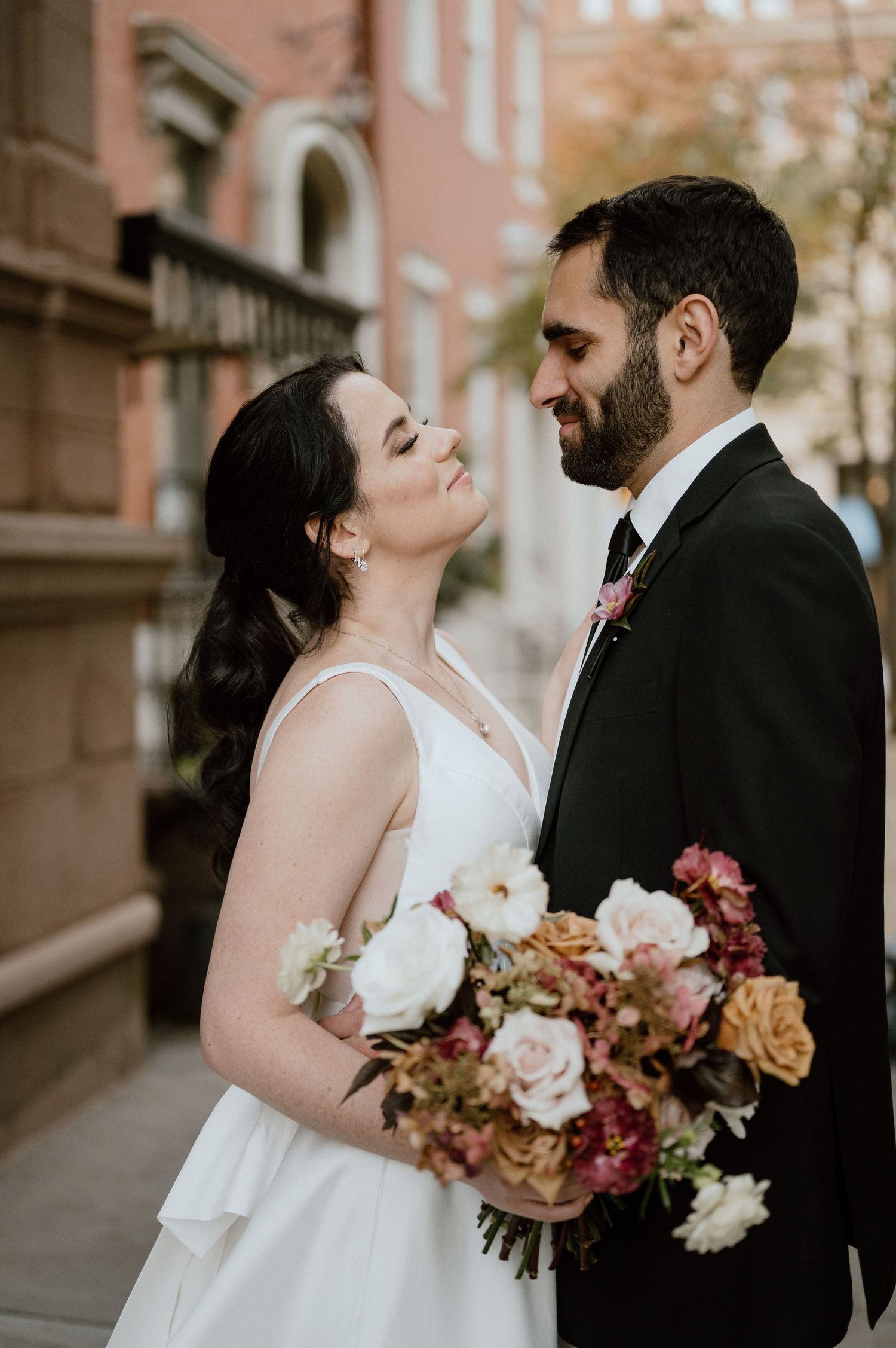 A tender wedding moment captured with beautiful autumn-toned flowers in the foreground.