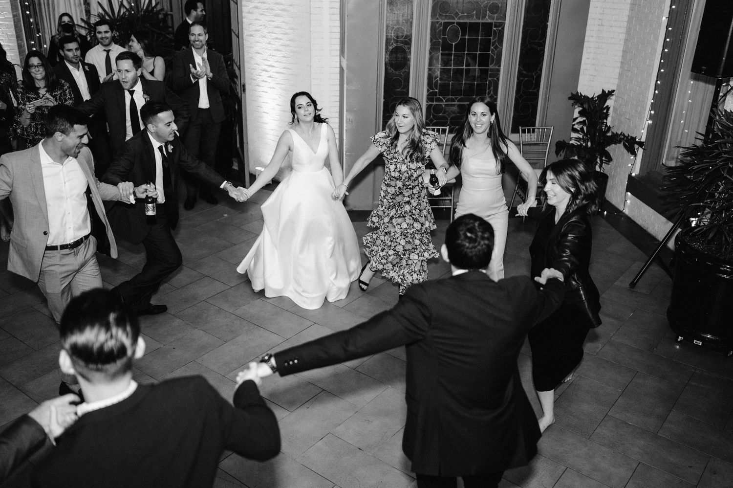 Black and white capture of wedding reception dance floor filled with joyful celebration.