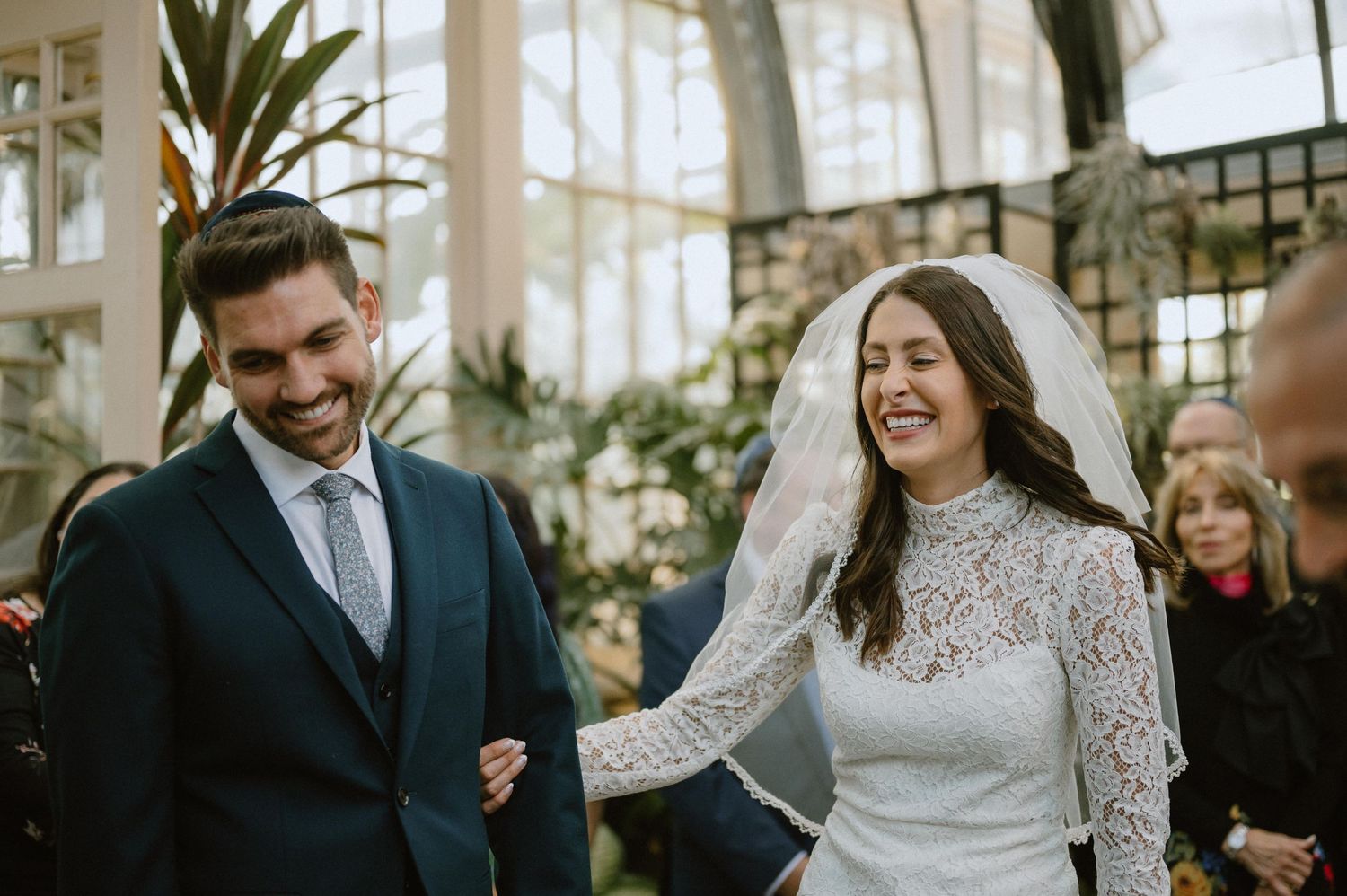 Happy couple shares joyful moment during greenhouse wedding ceremony.