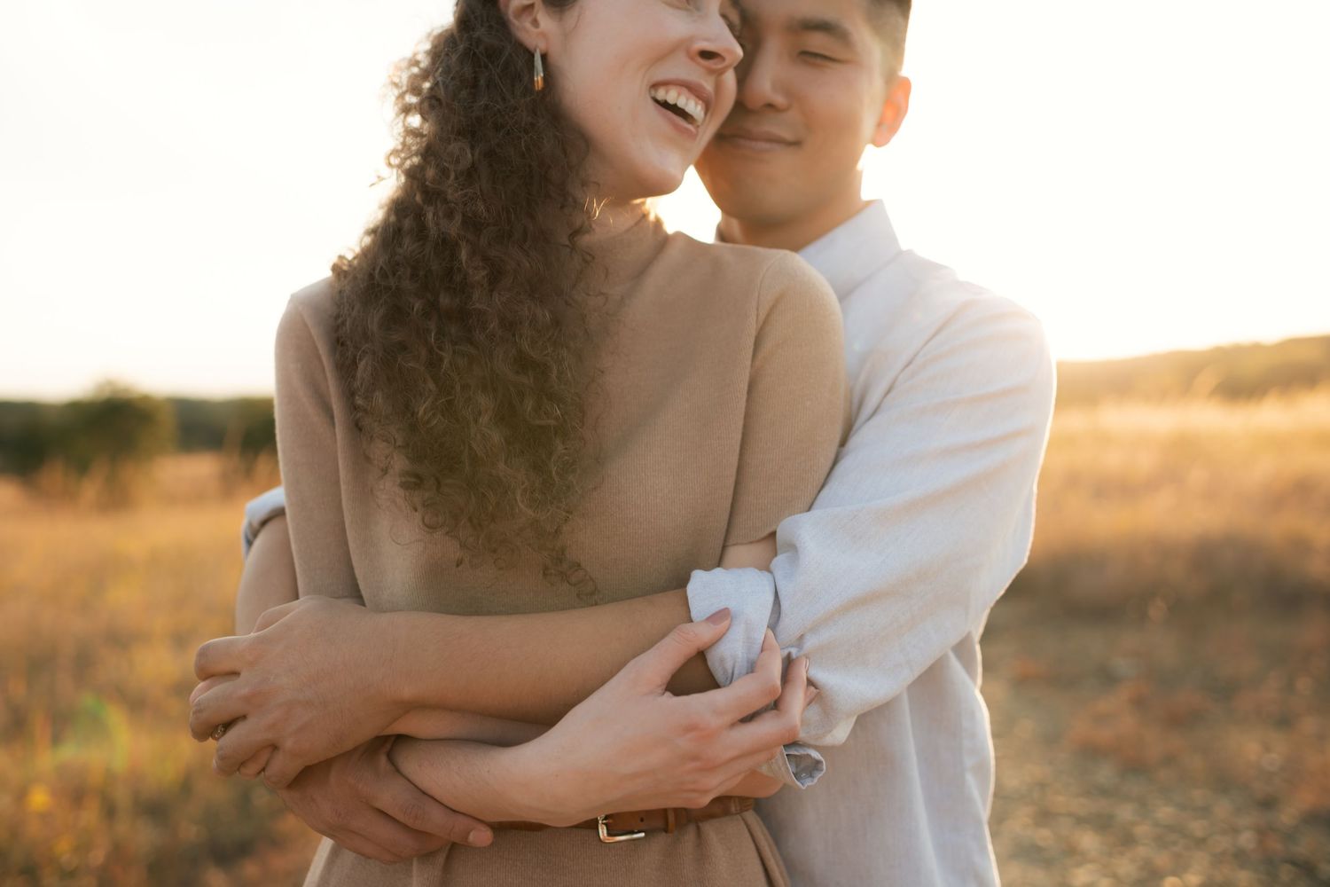 Couple sharing romantic moment in field during golden hour photography session.