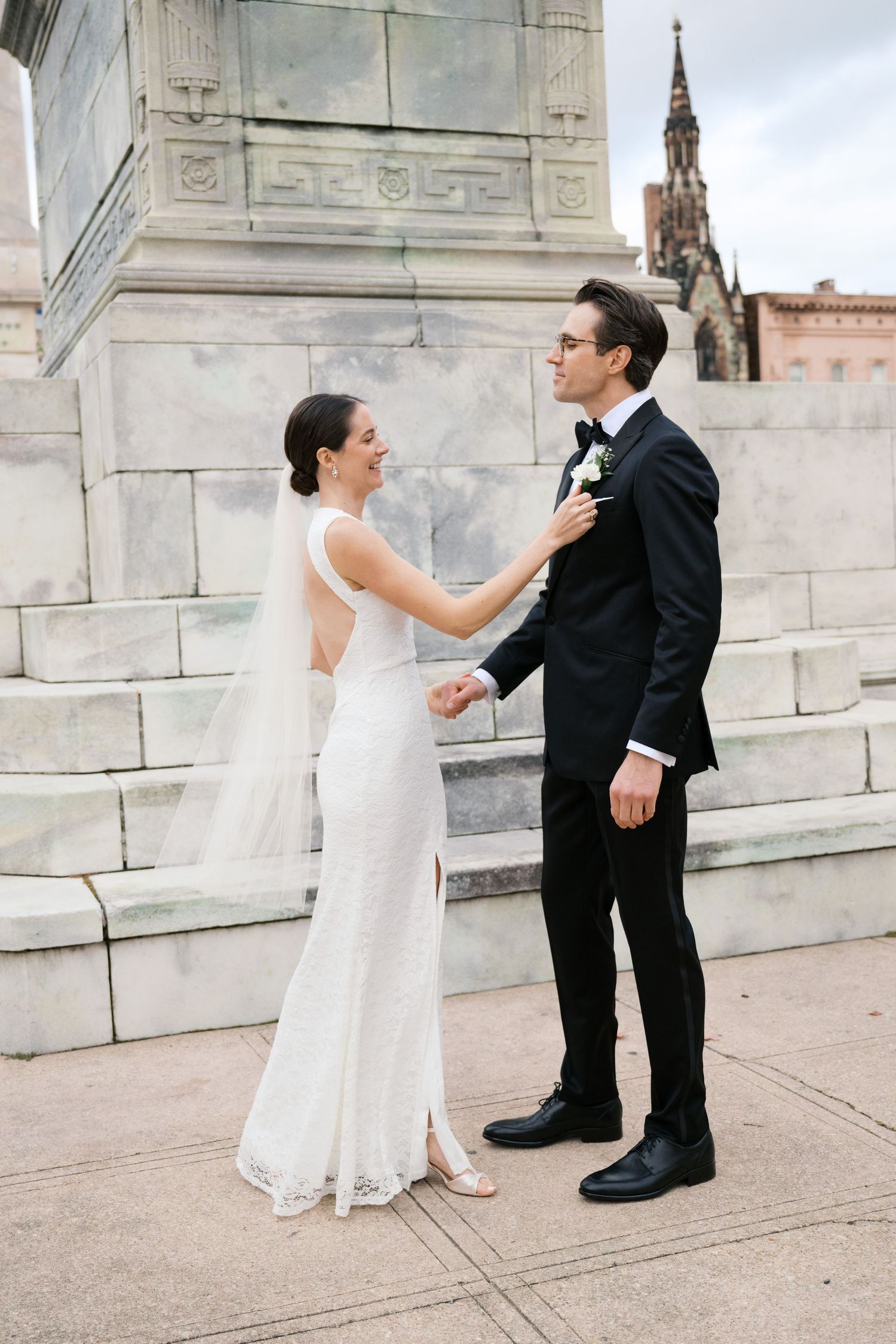Couple shares intimate moment on stone steps with historic church spire in background.