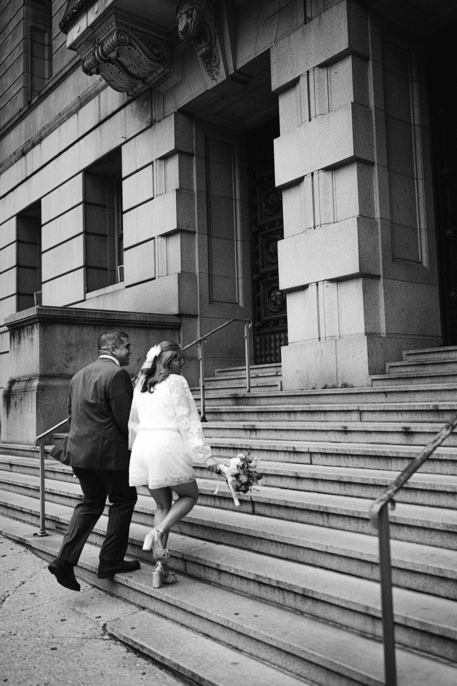 A couple ascending stone steps of a historic building in classic black and white photography.