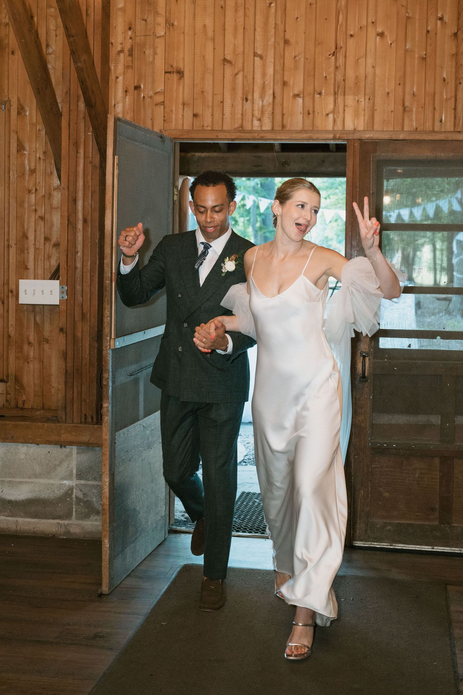 Celebratory entrance into rustic wooden venue with decorative lighting.