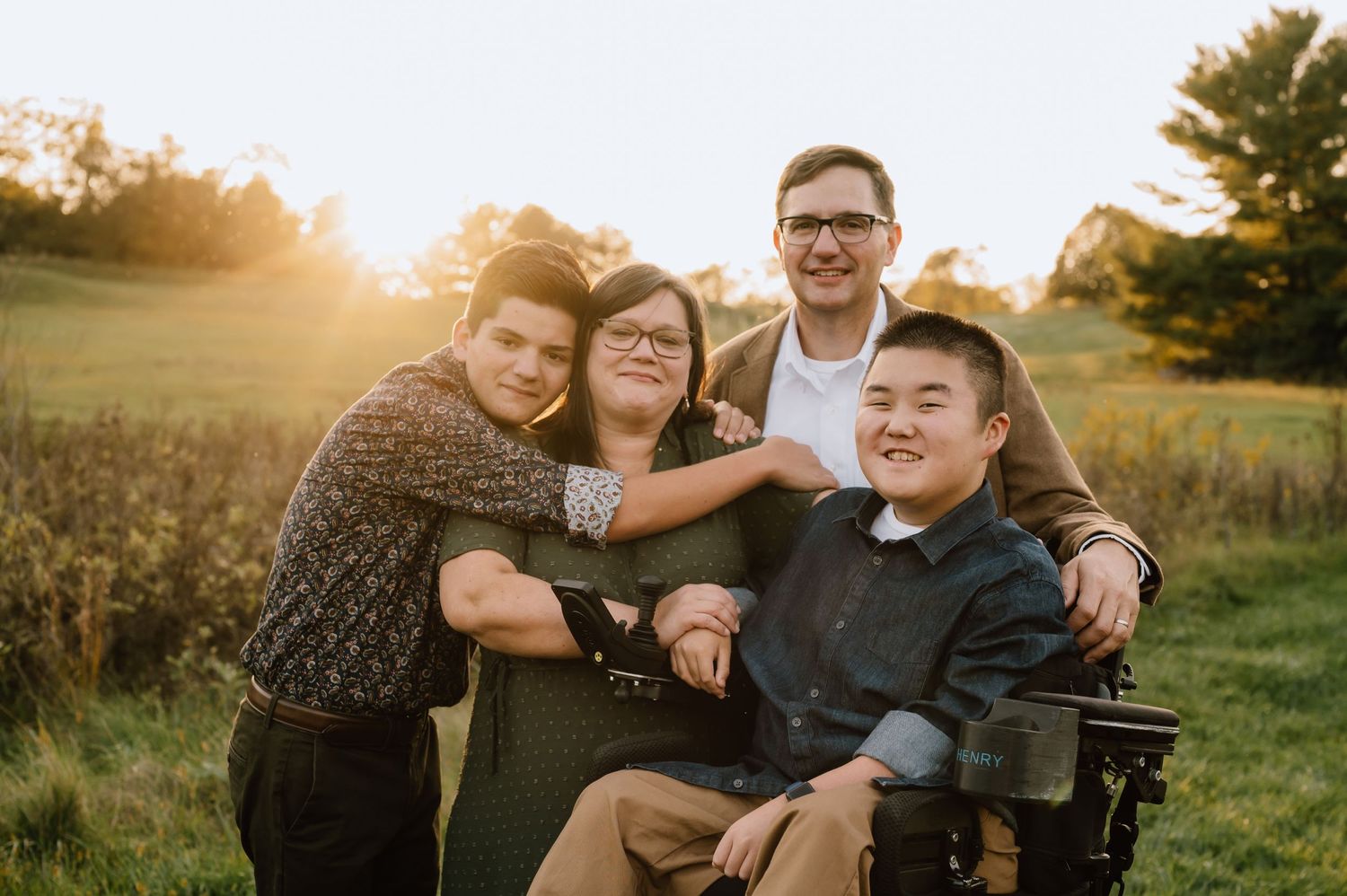 Warm sunset family portrait with group embracing outdoors in a natural setting.