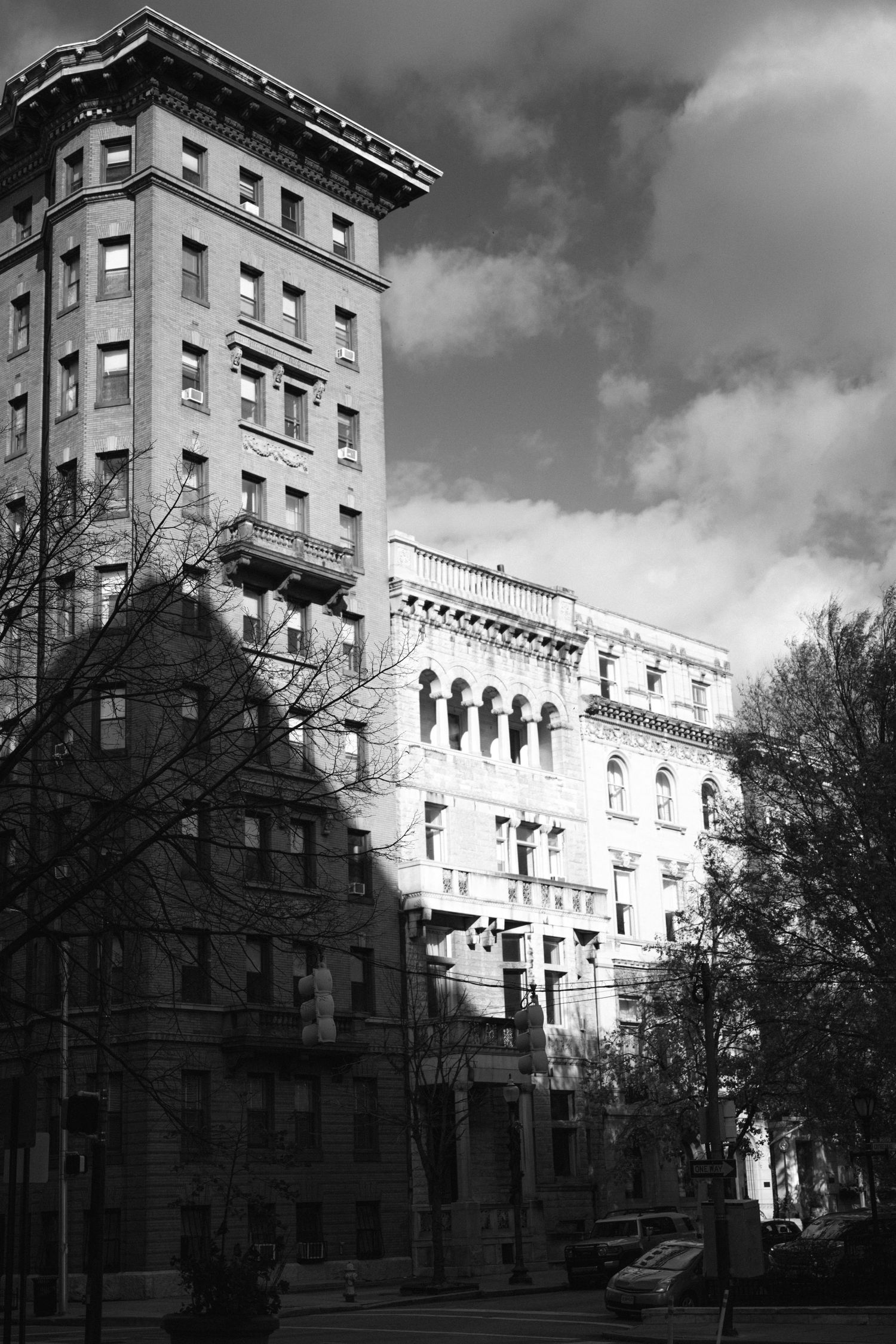 Historic apartment building with ornate architecture and dramatic cloudy sky in black and white.