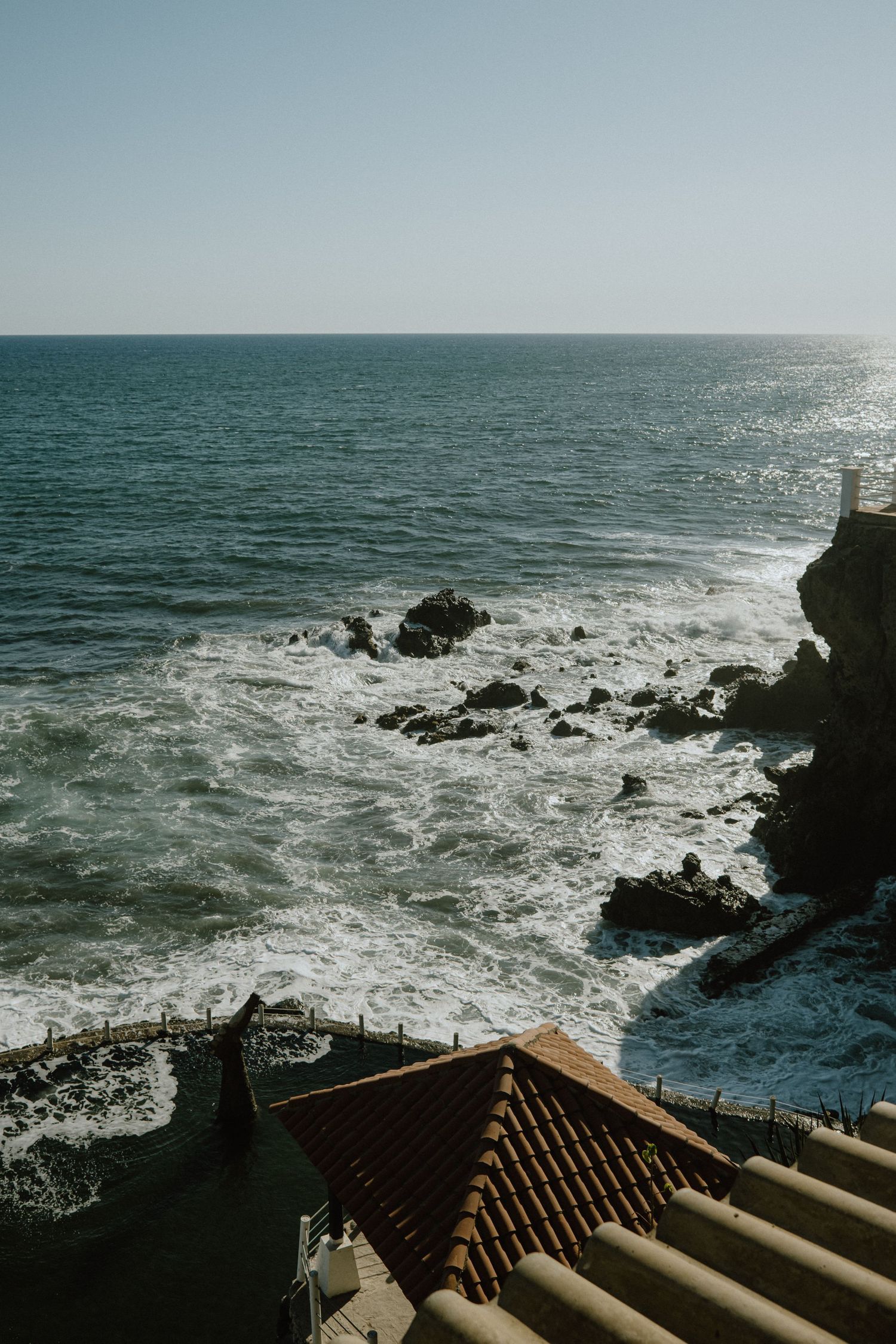 Coastal view with stone steps and agave plants overlooking rough ocean waves.