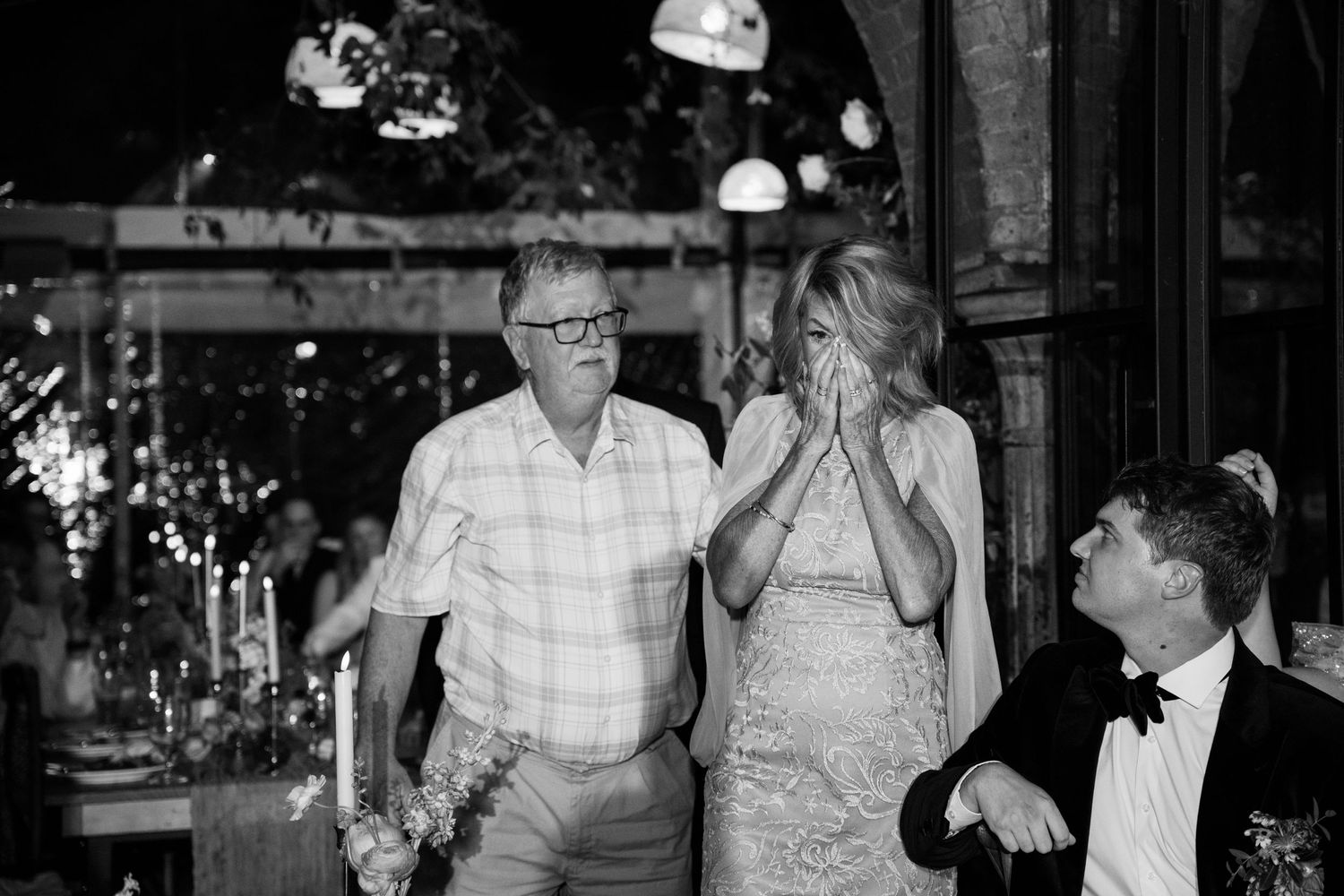 A candid black and white reception moment showing guests laughing and enjoying the celebration.