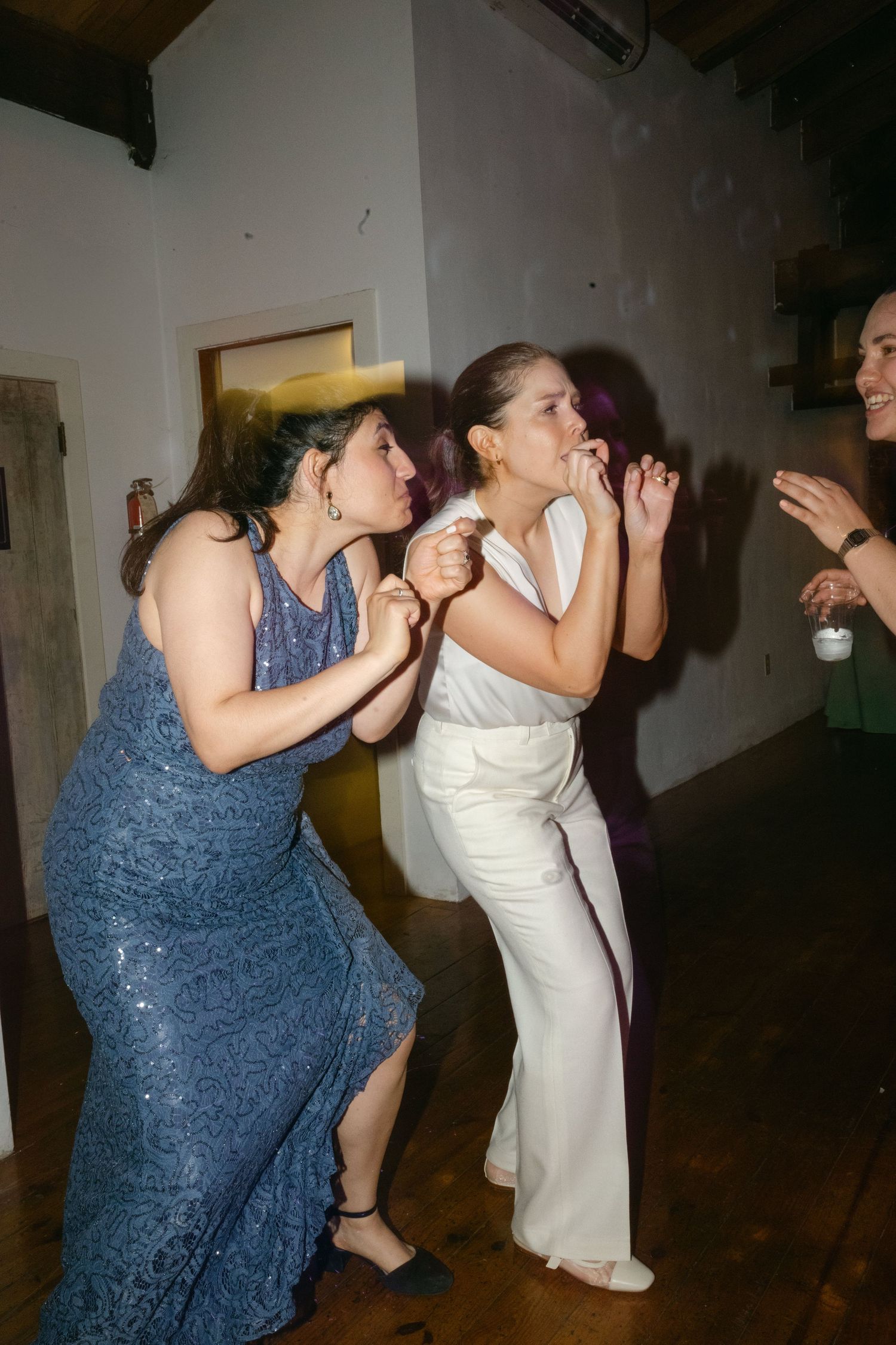 Wedding guests dancing together in a dimly lit venue with a fun celebratory atmosphere.
