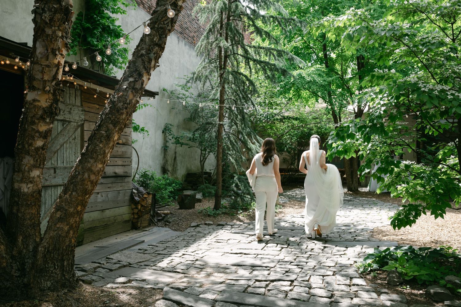 People walking along a stone pathway surrounded by lush green trees and foliage.