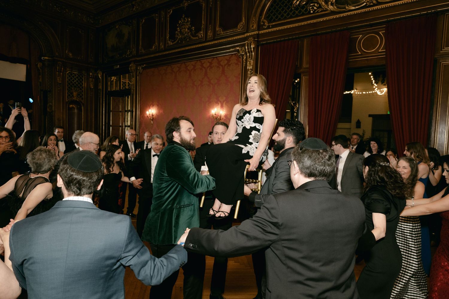 Wedding reception celebration with guests dancing and celebrating in an ornate ballroom.