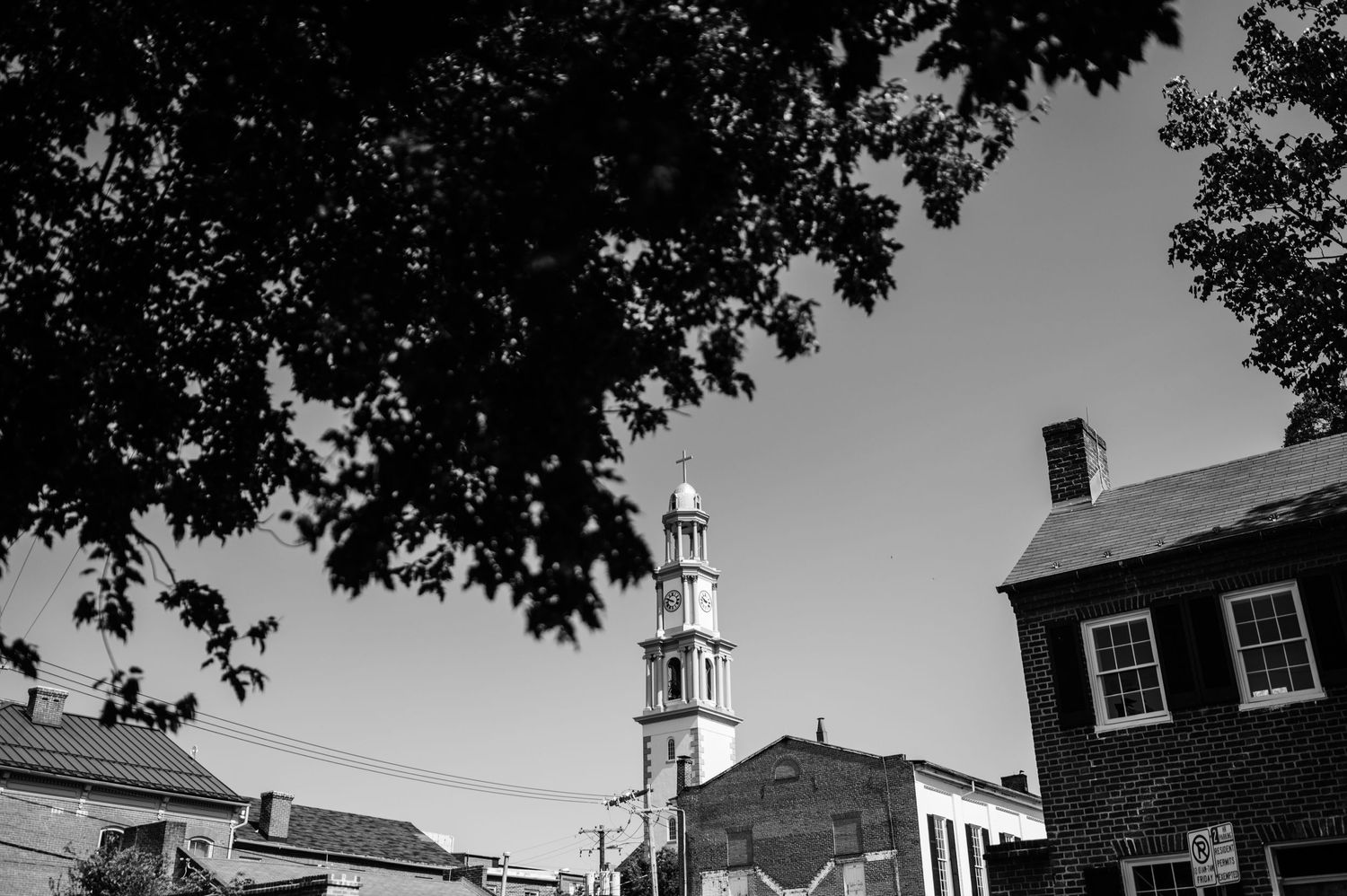 Black and white cityscape with church spire and brick buildings.