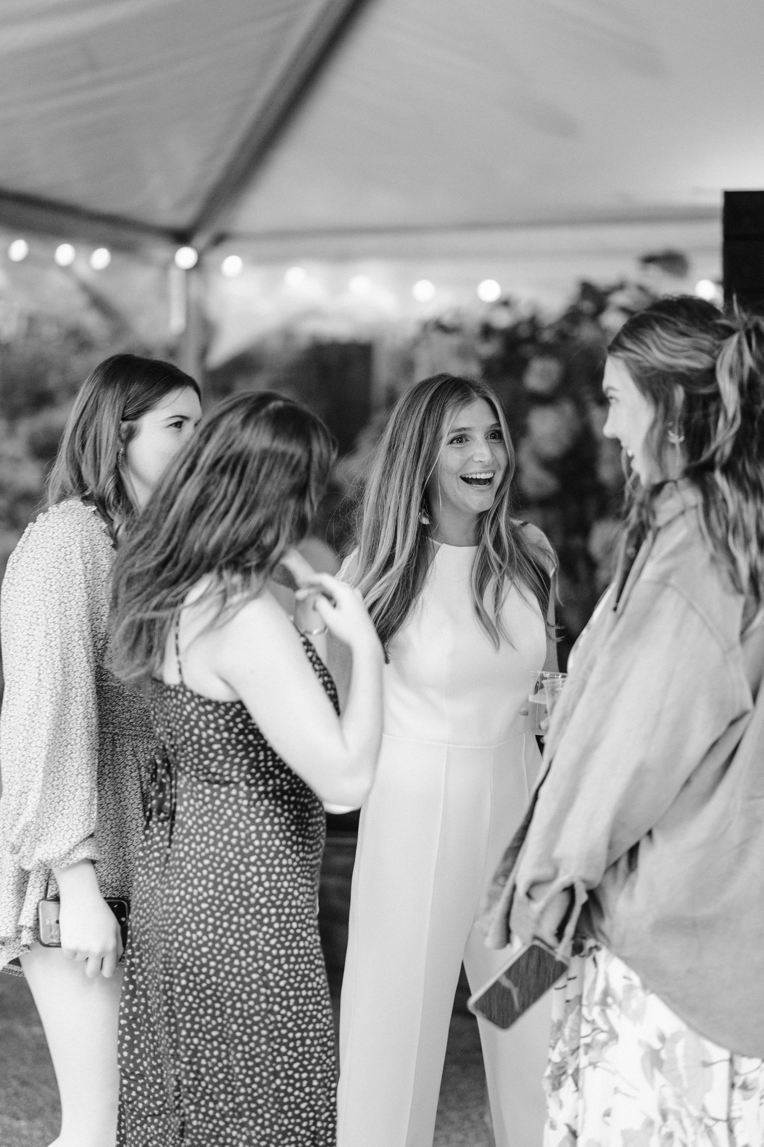 Group of wedding guests sharing joyful moment under reception tent.