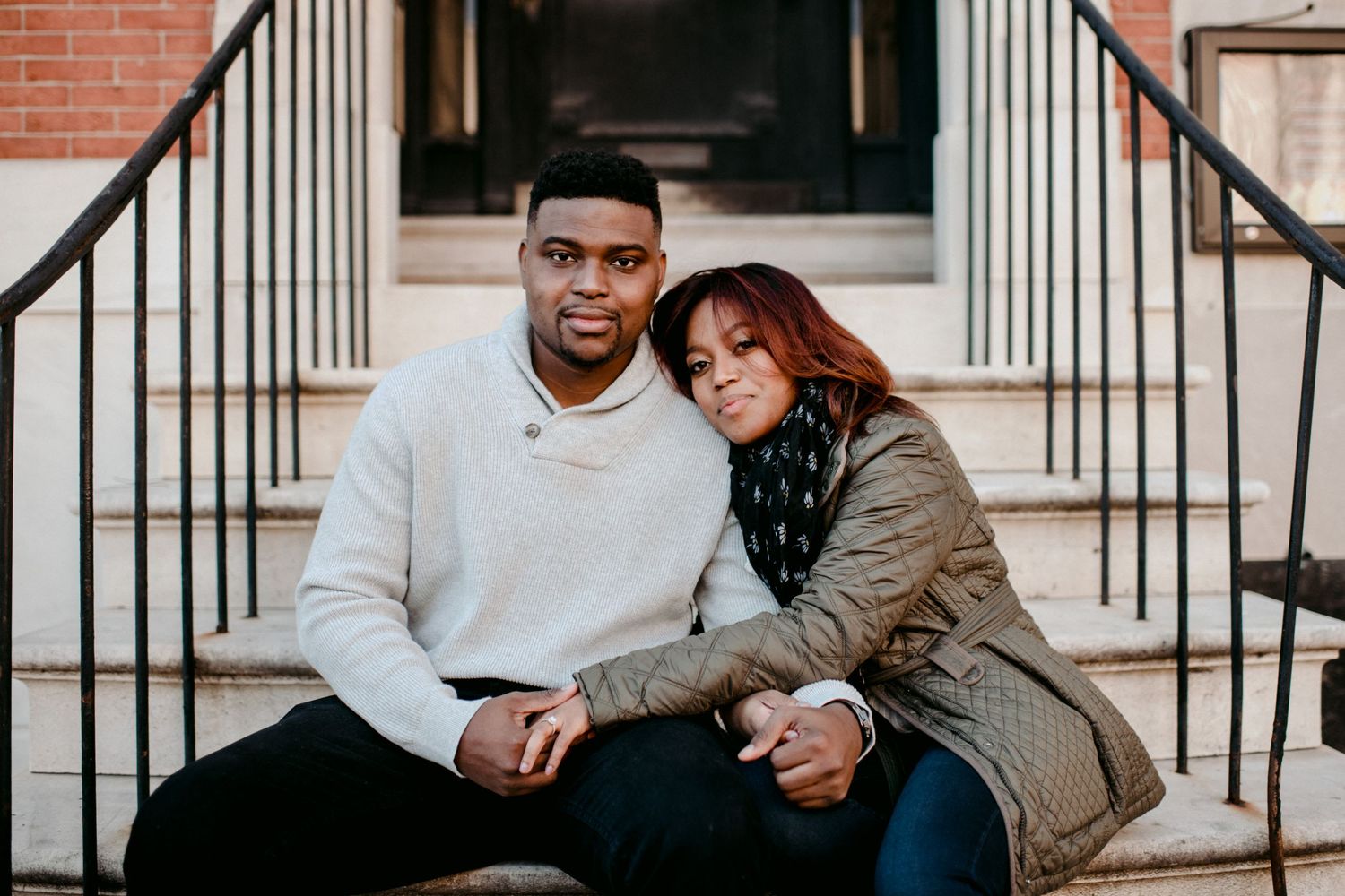 A couple sitting close together on urban brick steps during an engagement photoshoot.