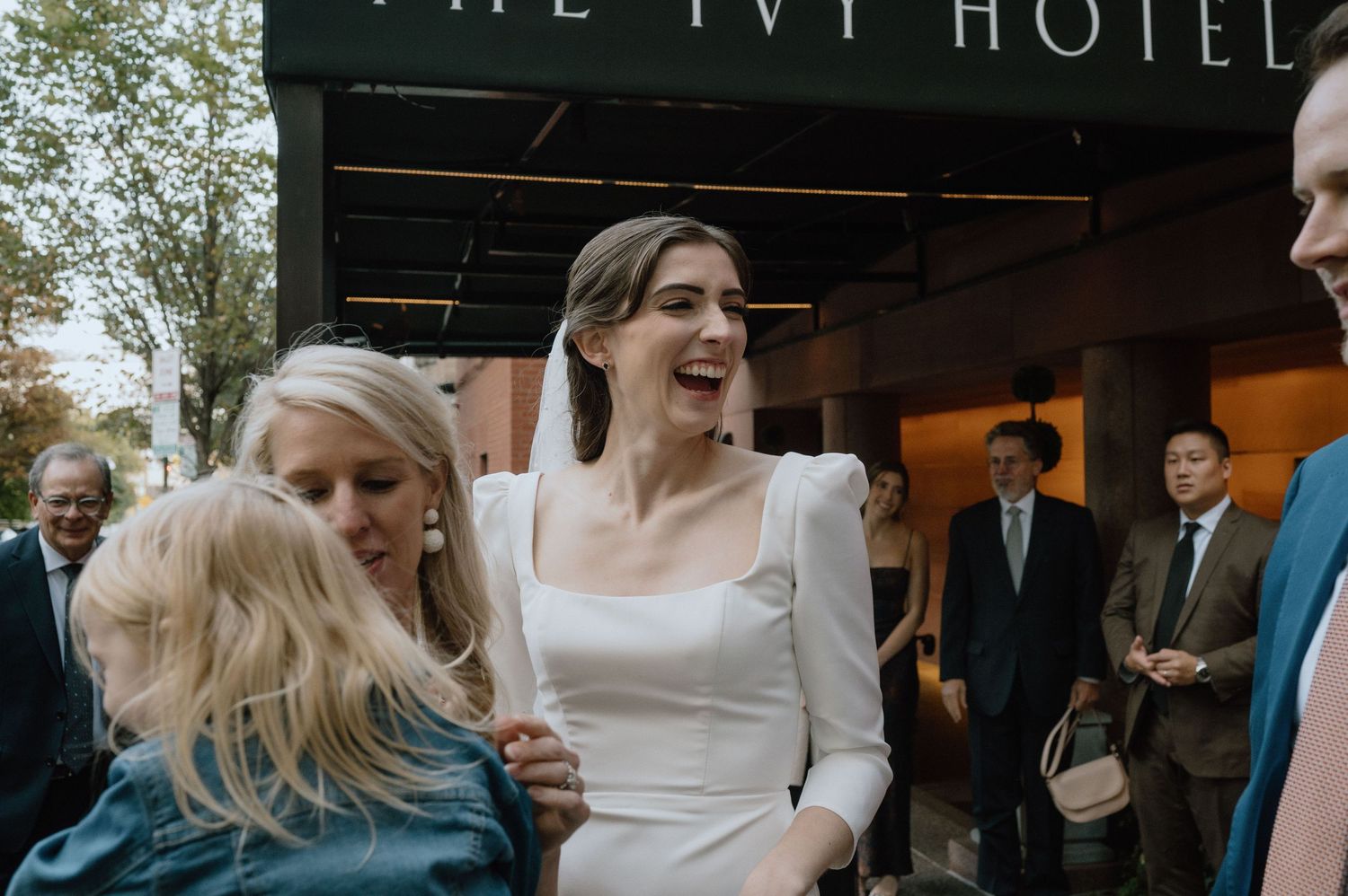 Wedding celebration outside The Ivy Hotel with guests sharing a candid moment.