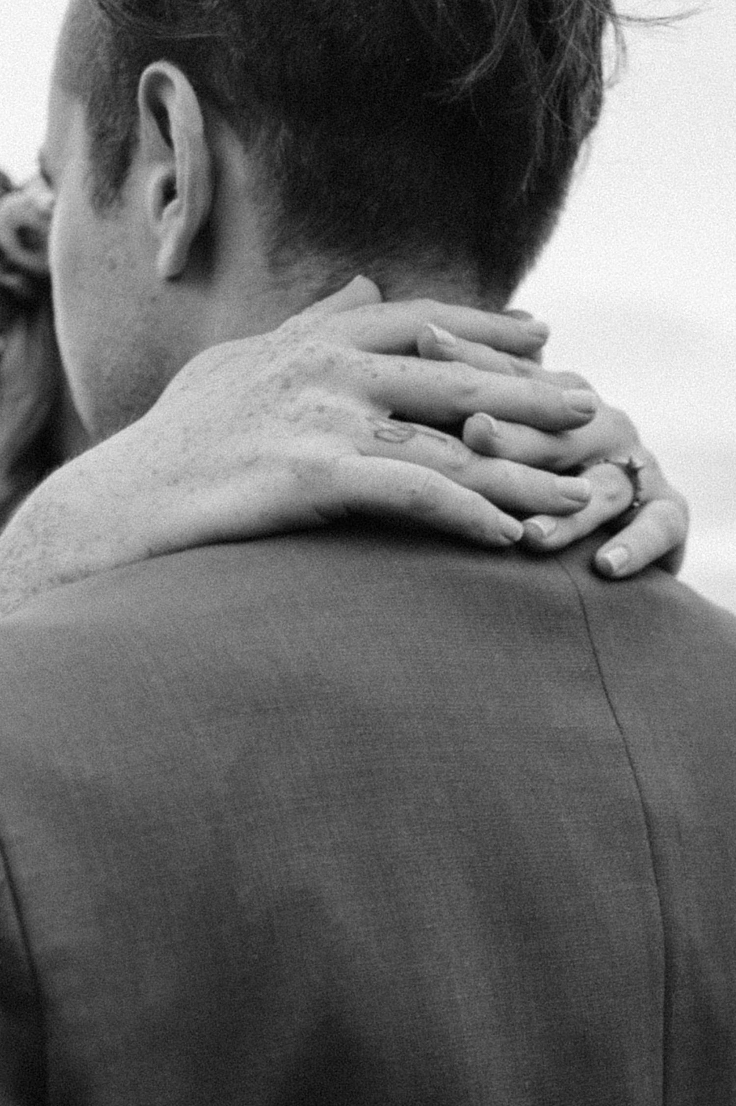 Black and white close-up of hands embracing on wedding day.