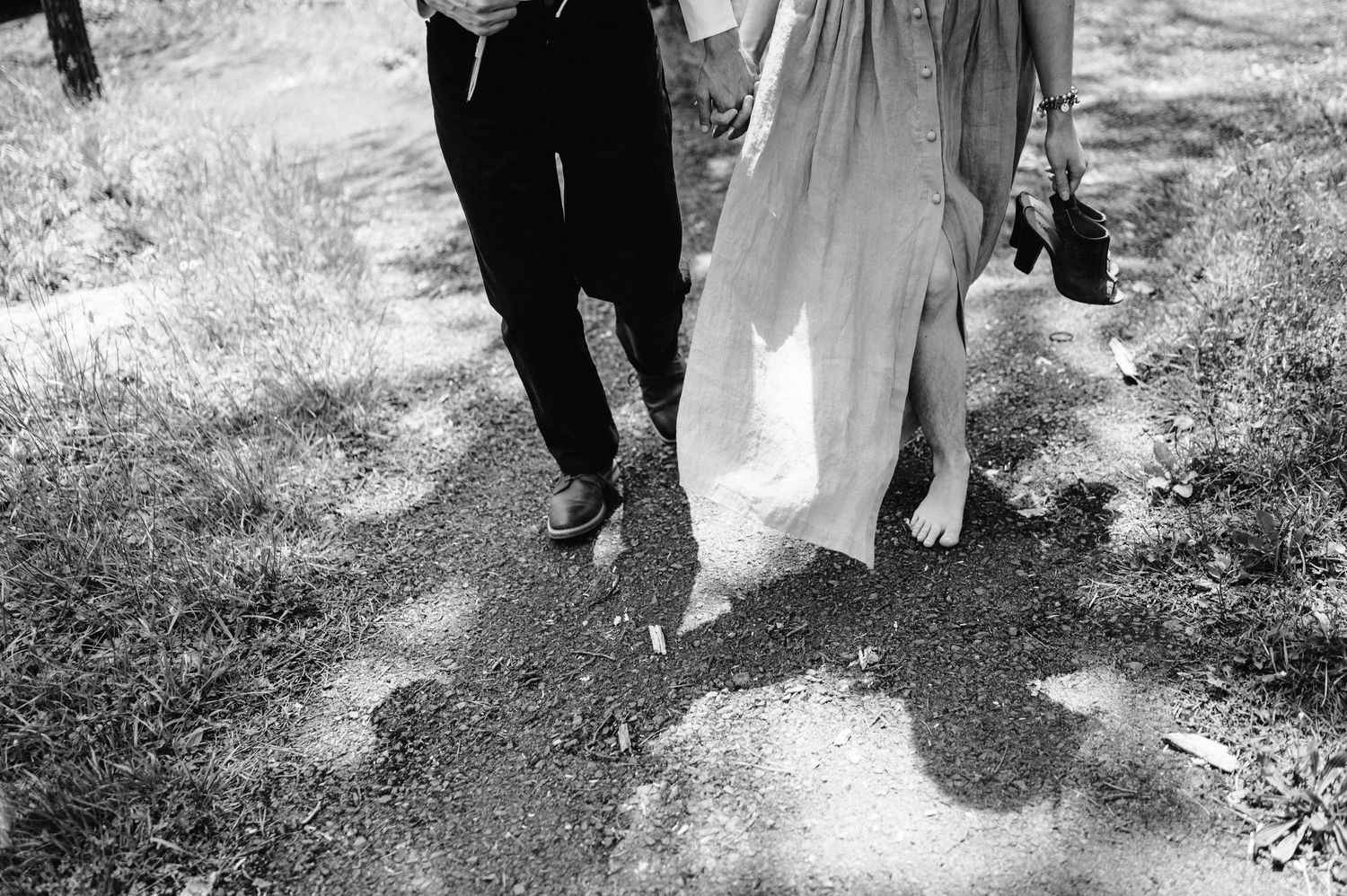 Black and white photo of two people walking together, showing only their lower bodies and casting shadows.