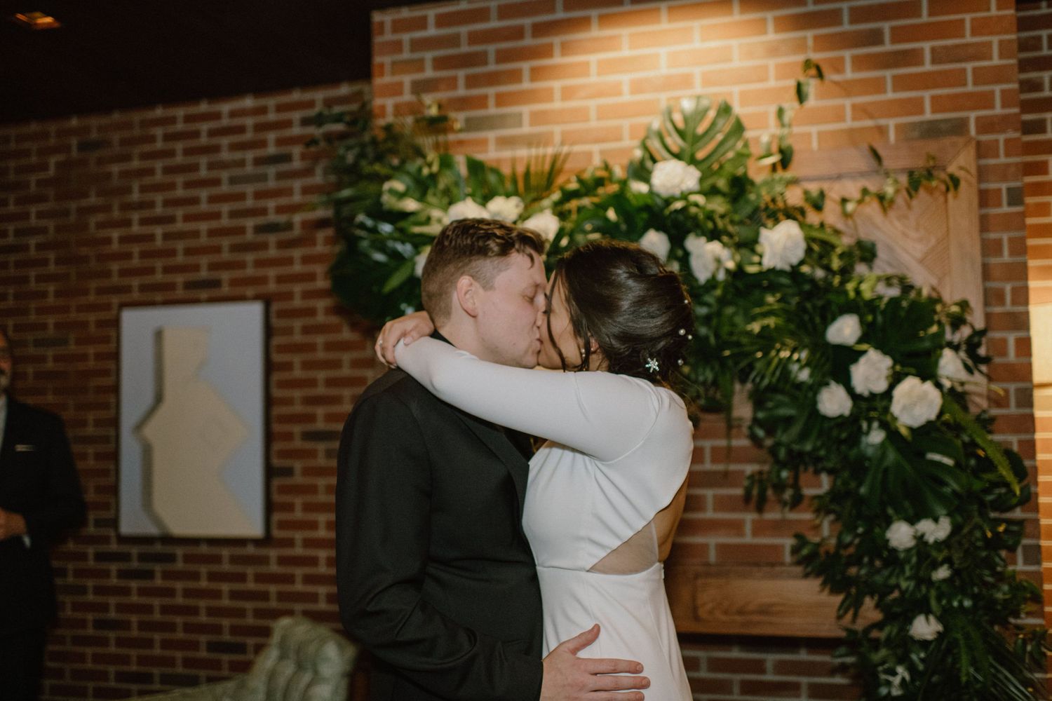 An intimate dance moment beneath floral decorations and warm lighting.