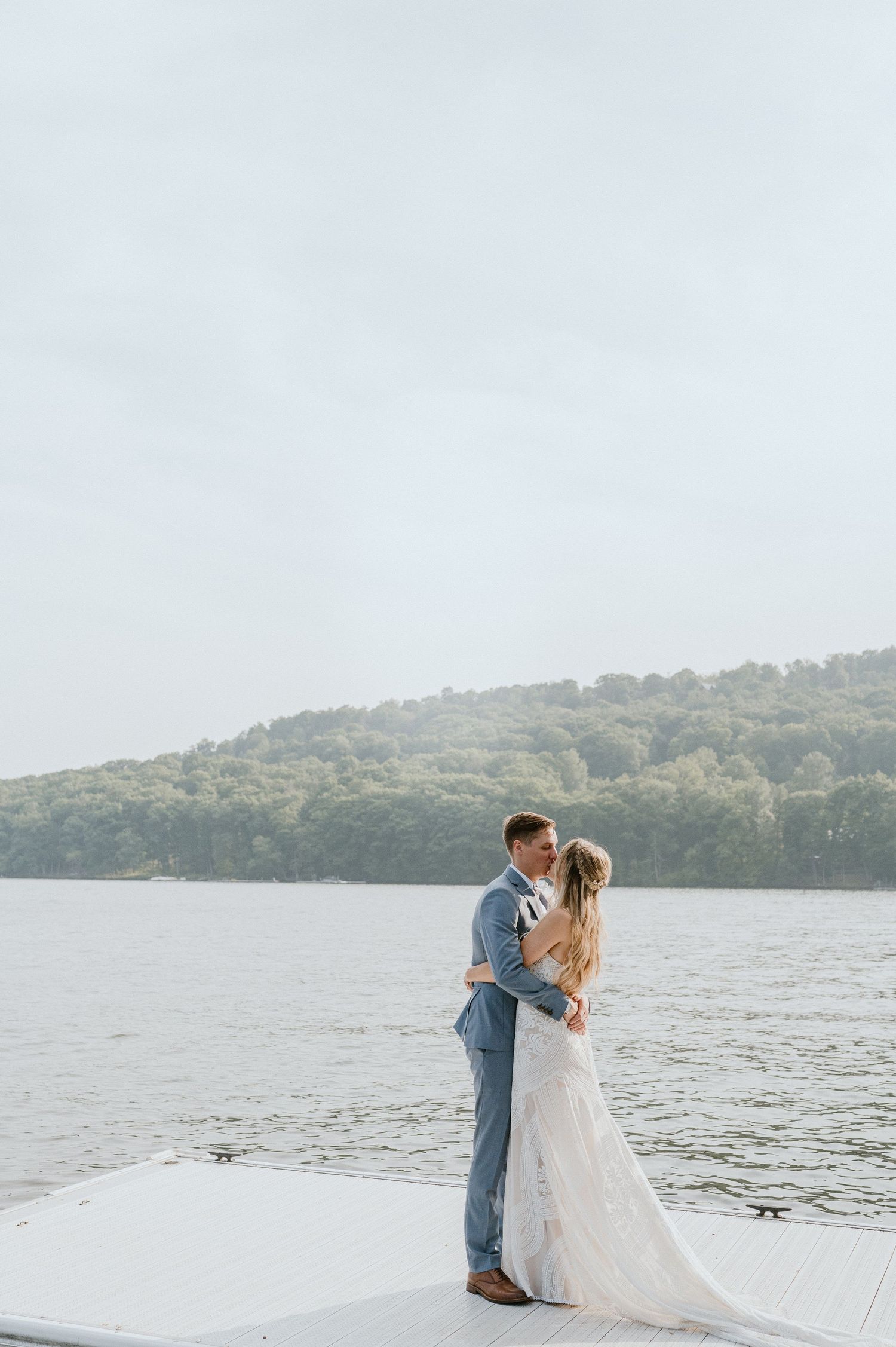 A romantic lakeside moment captured on a dock with mountains in the background.