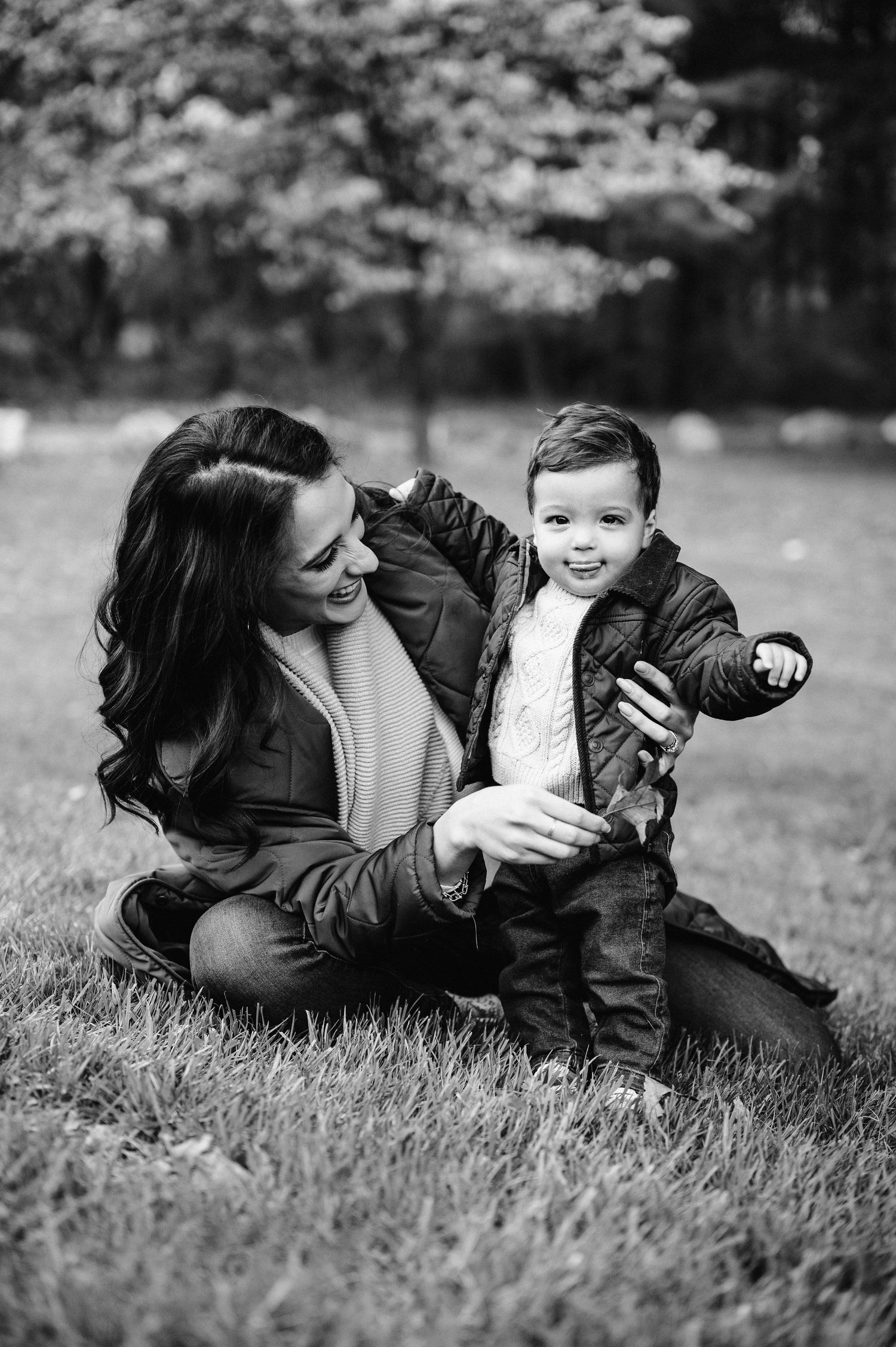 Black and white photo of playful outdoor moment with child in winter coat.
