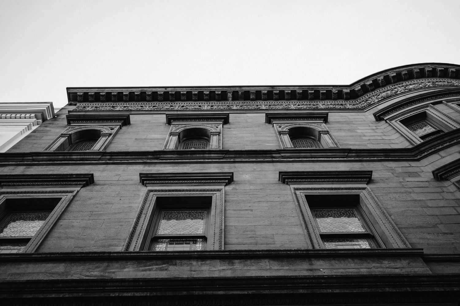 Black and white architectural photograph showing historic building windows and ornate stonework details.