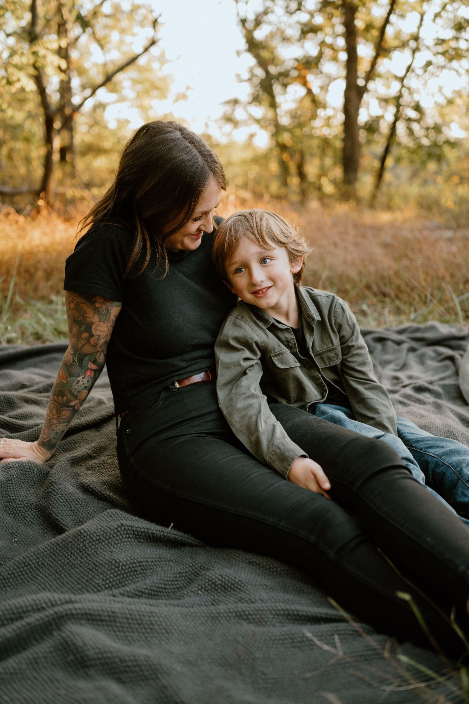 A warm autumn photoshoot featuring two people relaxing on a blanket in golden sunlight.