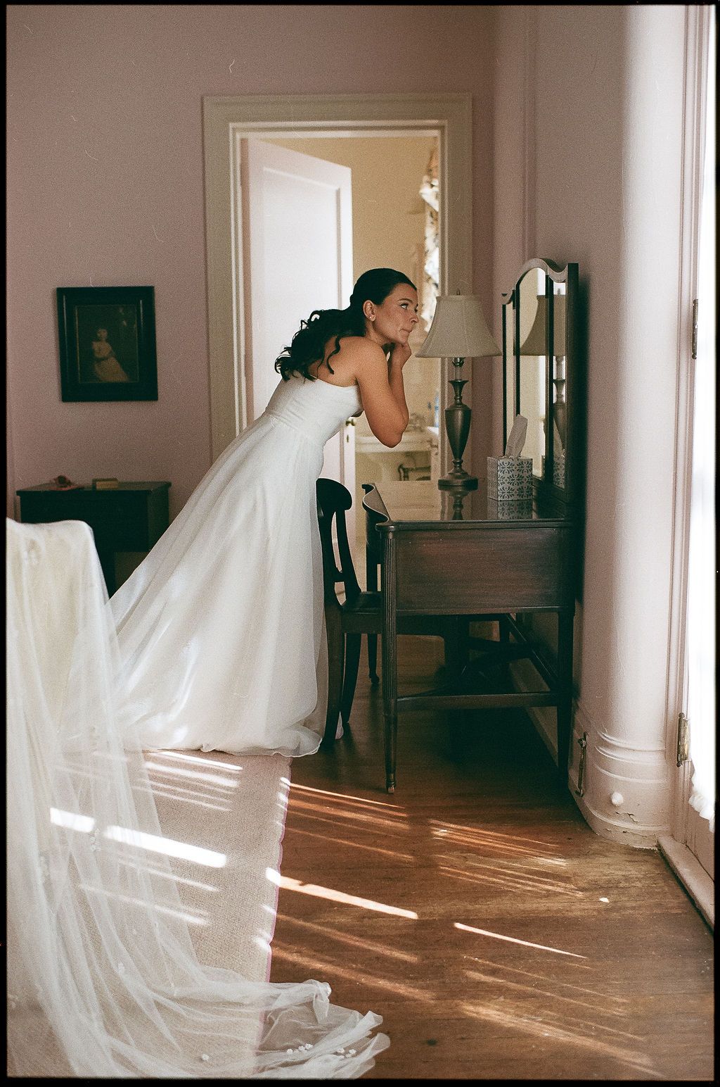 Sunlight streams across hardwood floors as a white wedding dress flows through a hallway.
