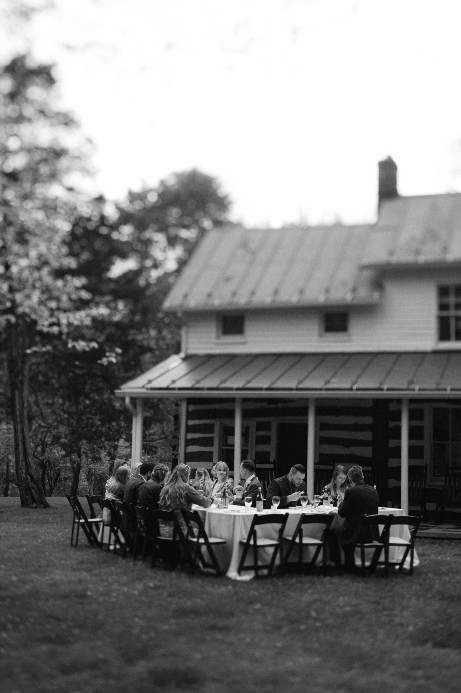 Black and white photos show a series of rocking chairs on a porch of a rural house with a metal roof.