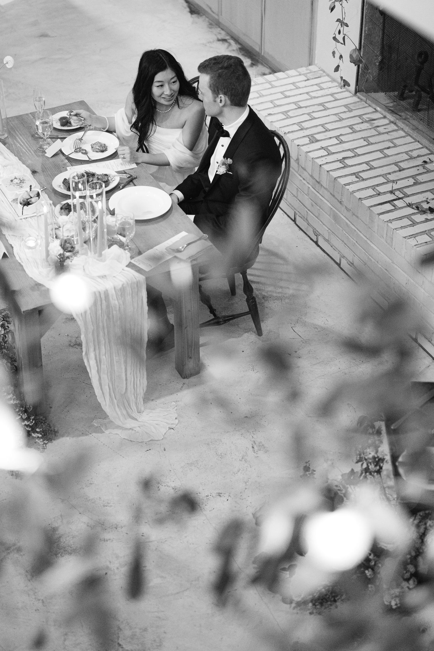Wedding reception dinner scene with table settings and decorative lighting.