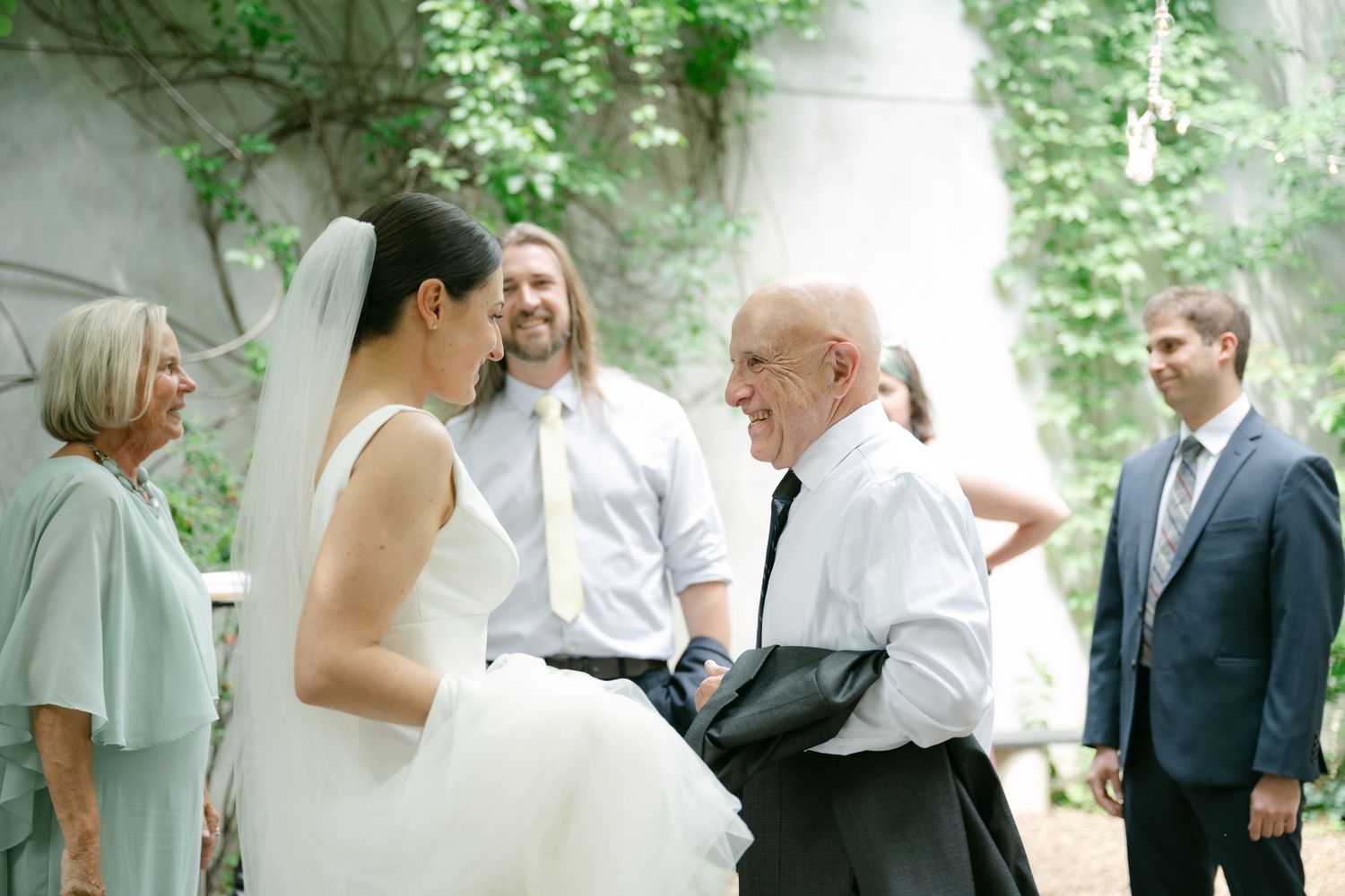 Wedding guests share joyful moments mingling and conversing at an outdoor garden reception.