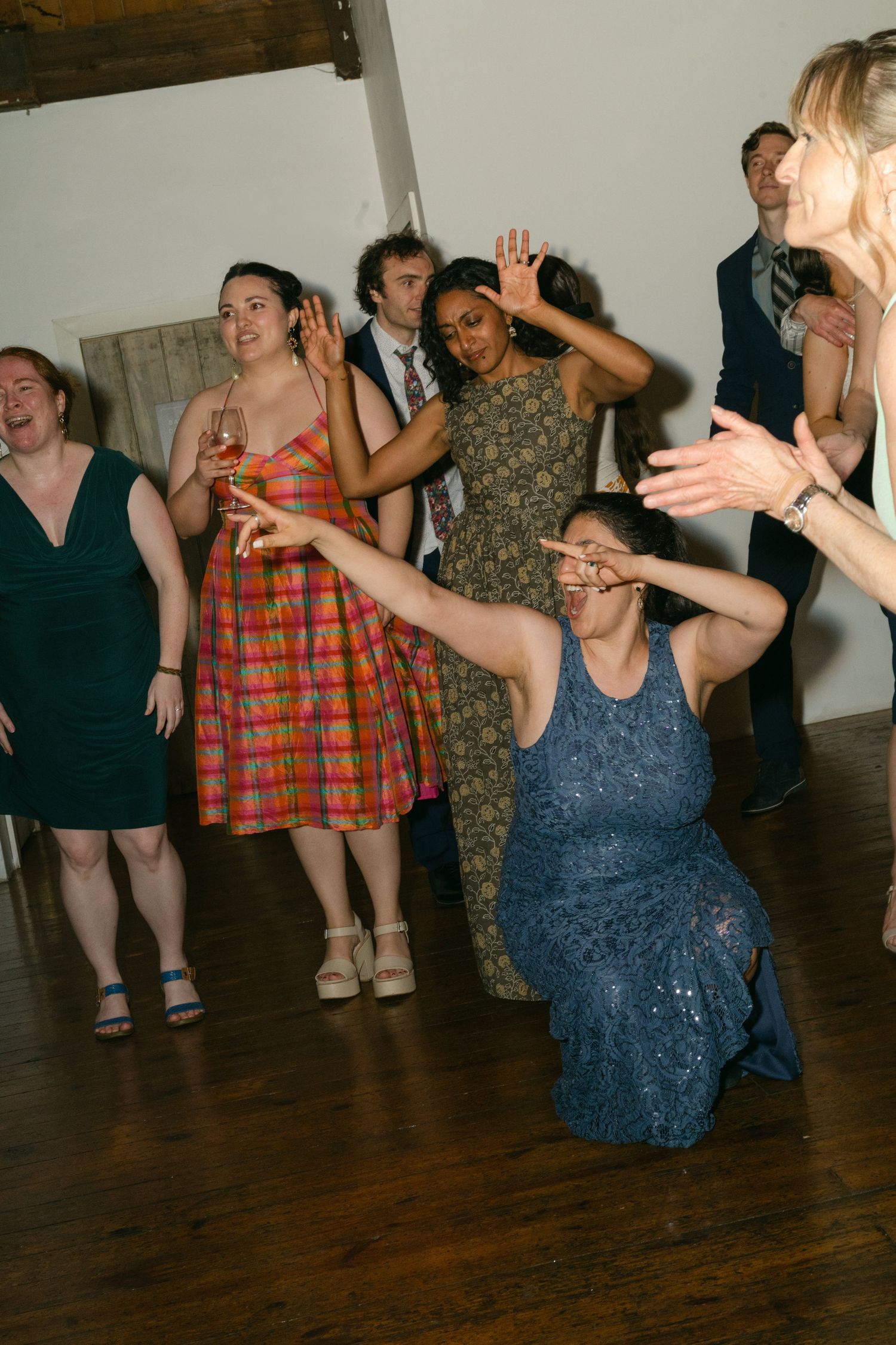 Party guests dancing enthusiastically on a dark hardwood floor at a celebration event.