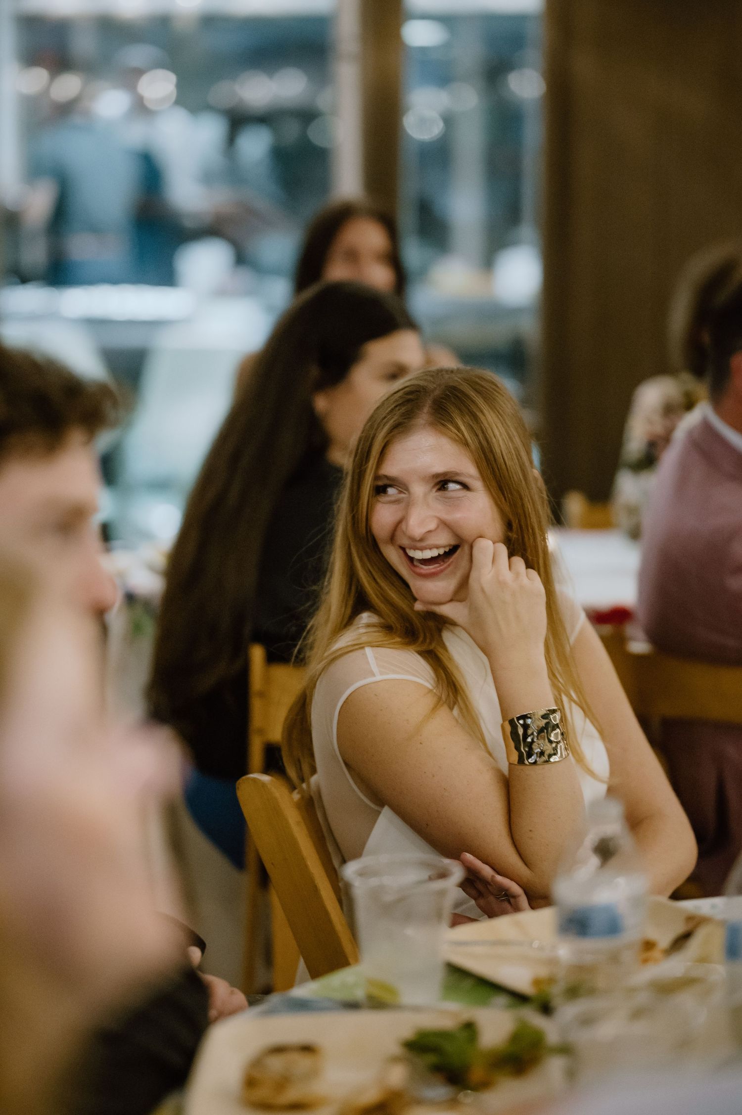 Wedding guest smiling joyfully during a dinner reception at a restaurant.