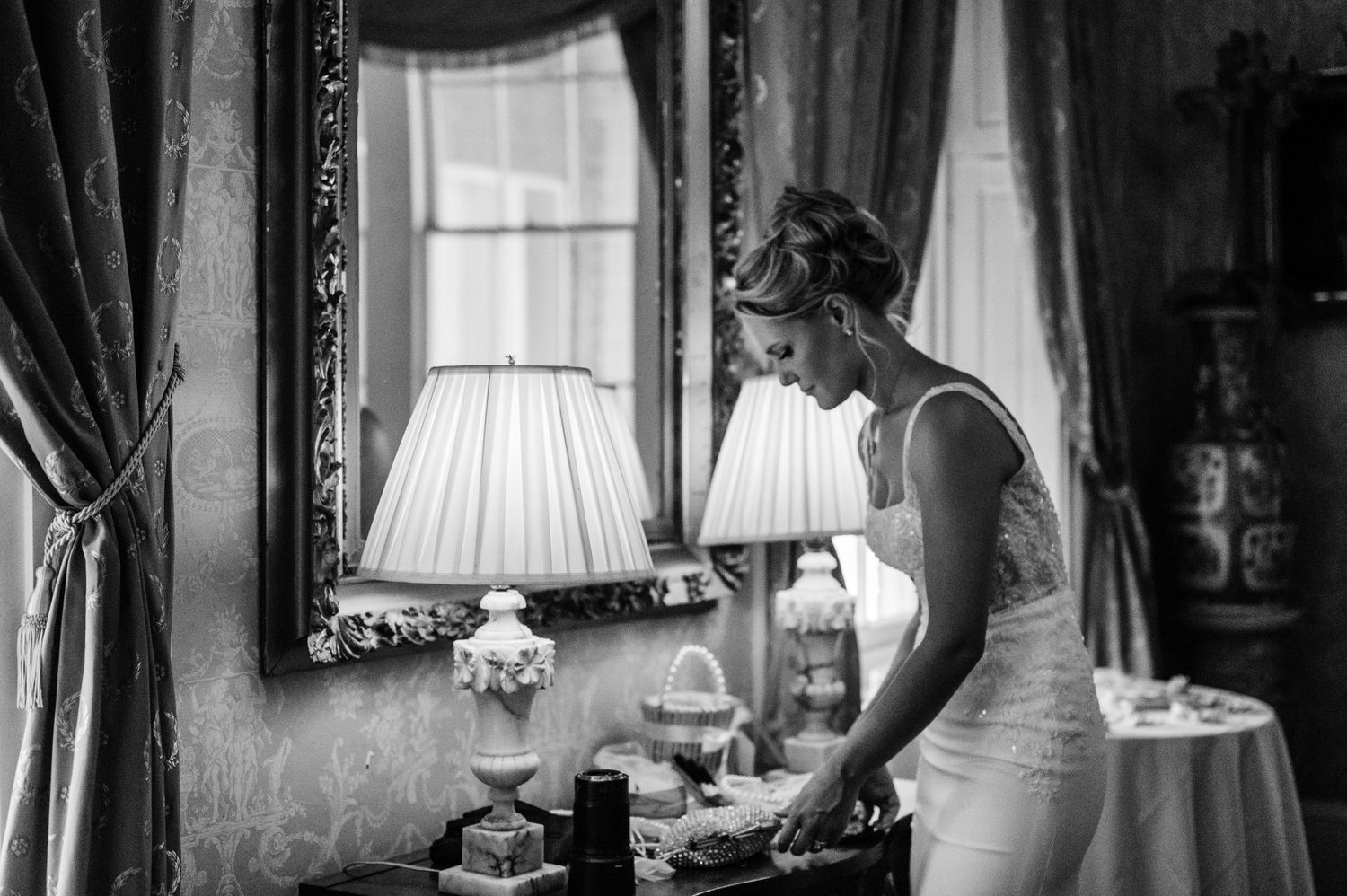 Black and white photograph of elegant interior with ornate mirror and vintage decor.