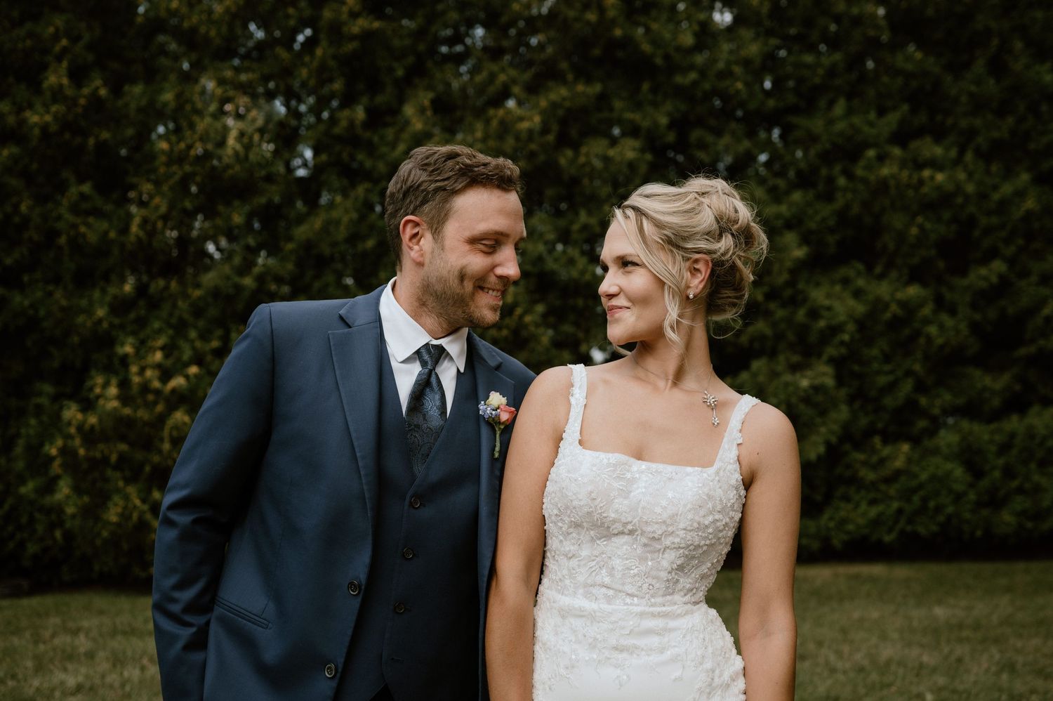 A couple shares a tender moment during their wedding photoshoot in a garden setting.
