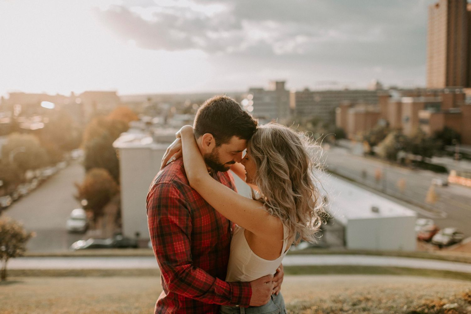 Romantic rooftop embrace with urban sunset backdrop.
