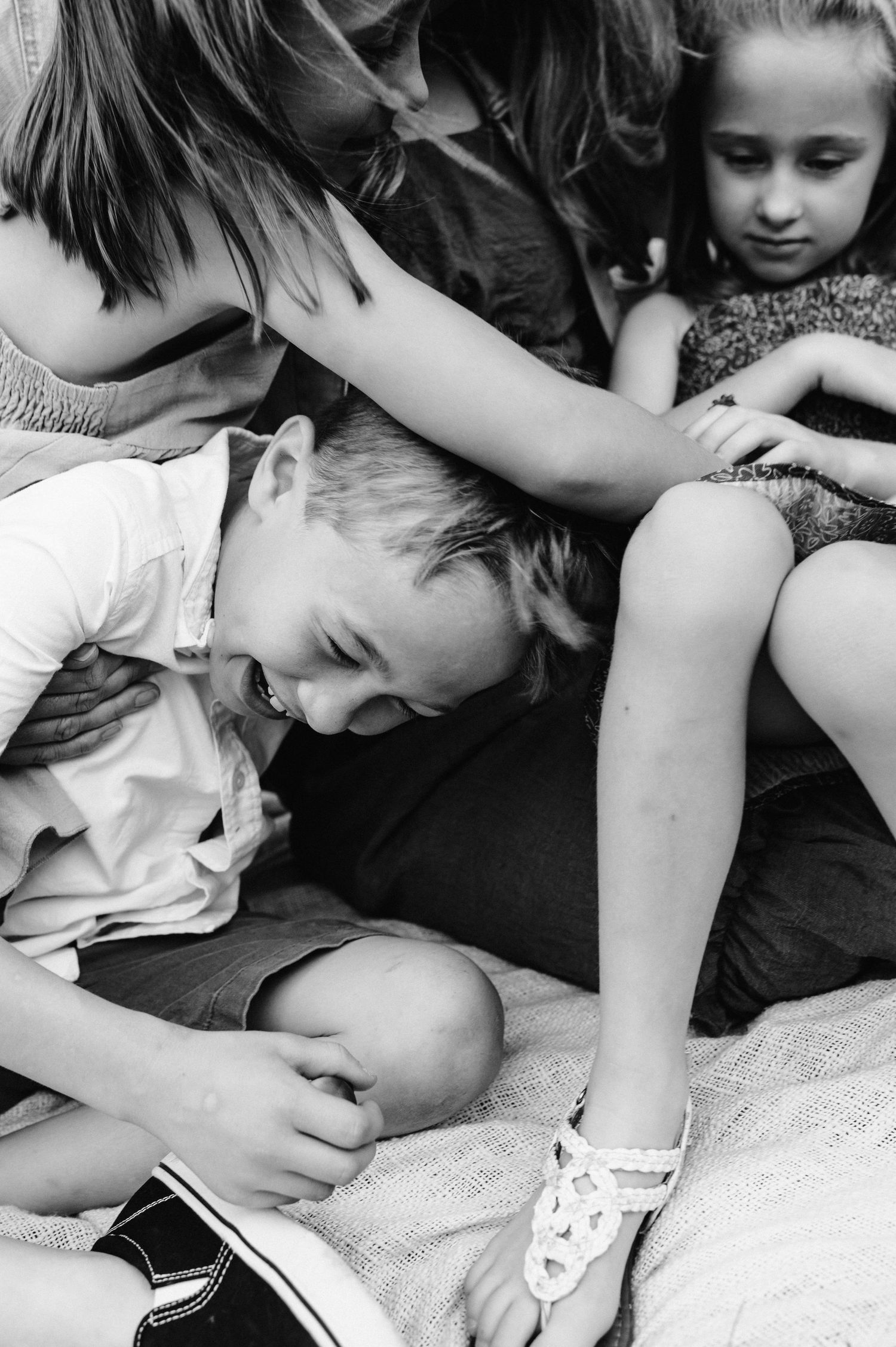 Close-up black and white photo showing intimate family interactions while relaxing together outdoors.