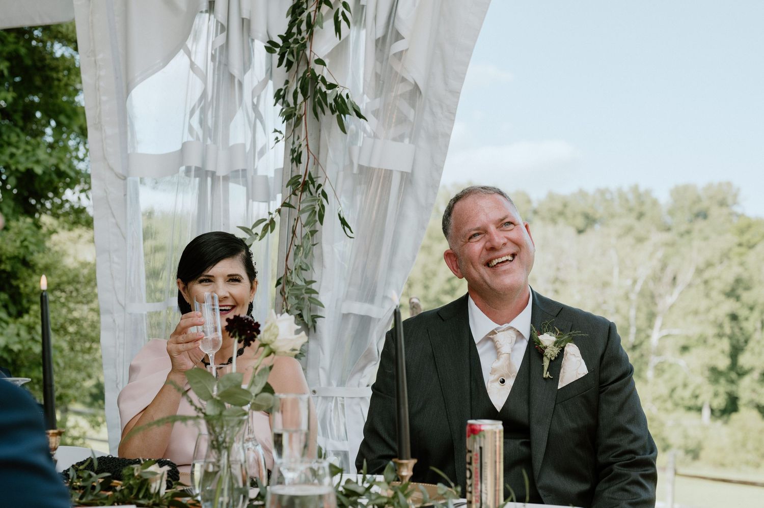 Wedding guests reacting with laughter during reception speeches.