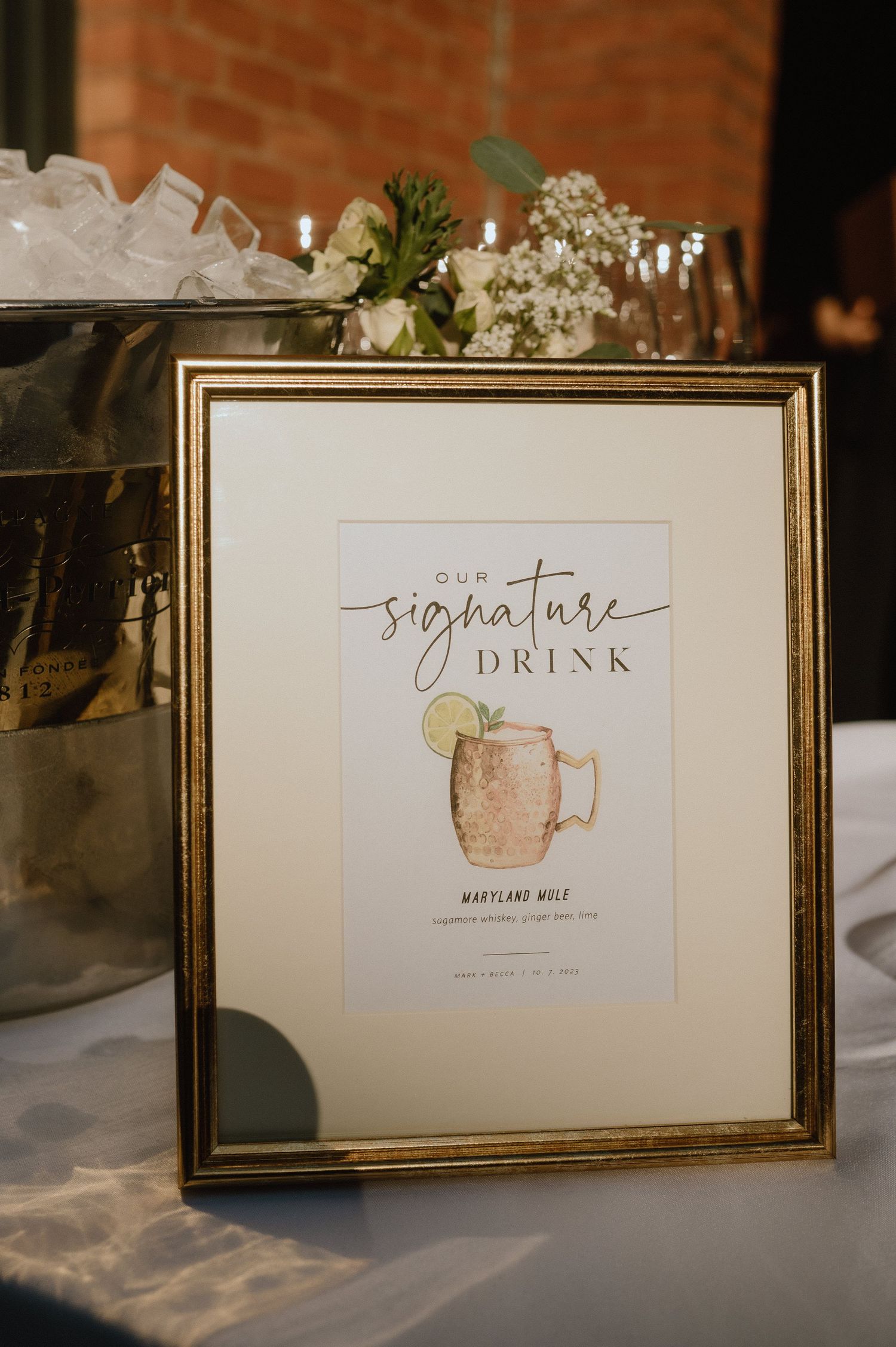 Framed signature drink menu with watercolor cocktail illustration in gold frame.