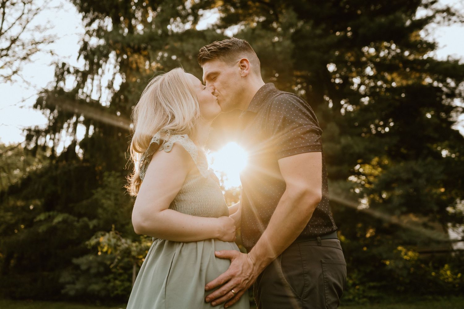 A romantic sunset moment captured in a garden with golden sunlight peeking through evergreen trees.
