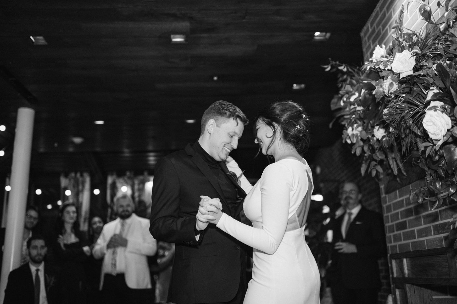 A couple shares their first dance at a dimly lit wedding reception.