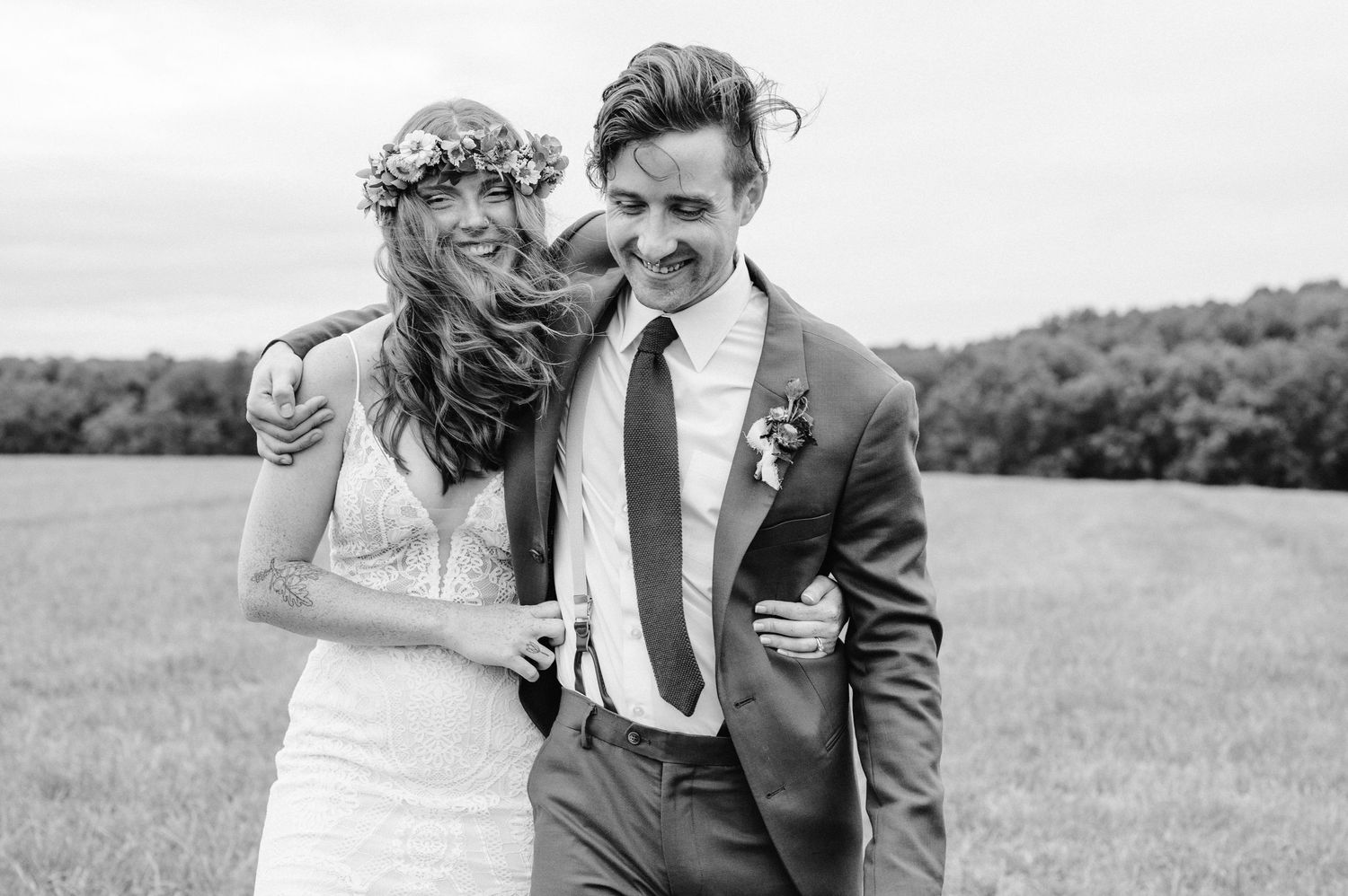 Black and white candid wedding portrait in field with flower crown.
