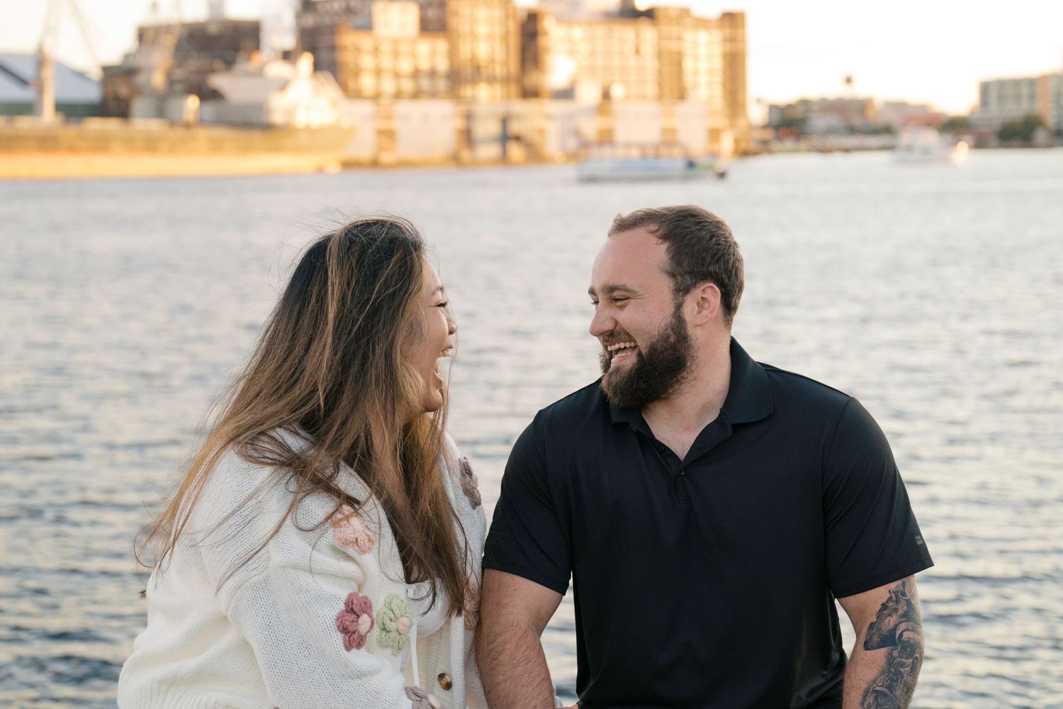 A couple sits near the waterfront at sunset sharing a romantic moment on the dock.
