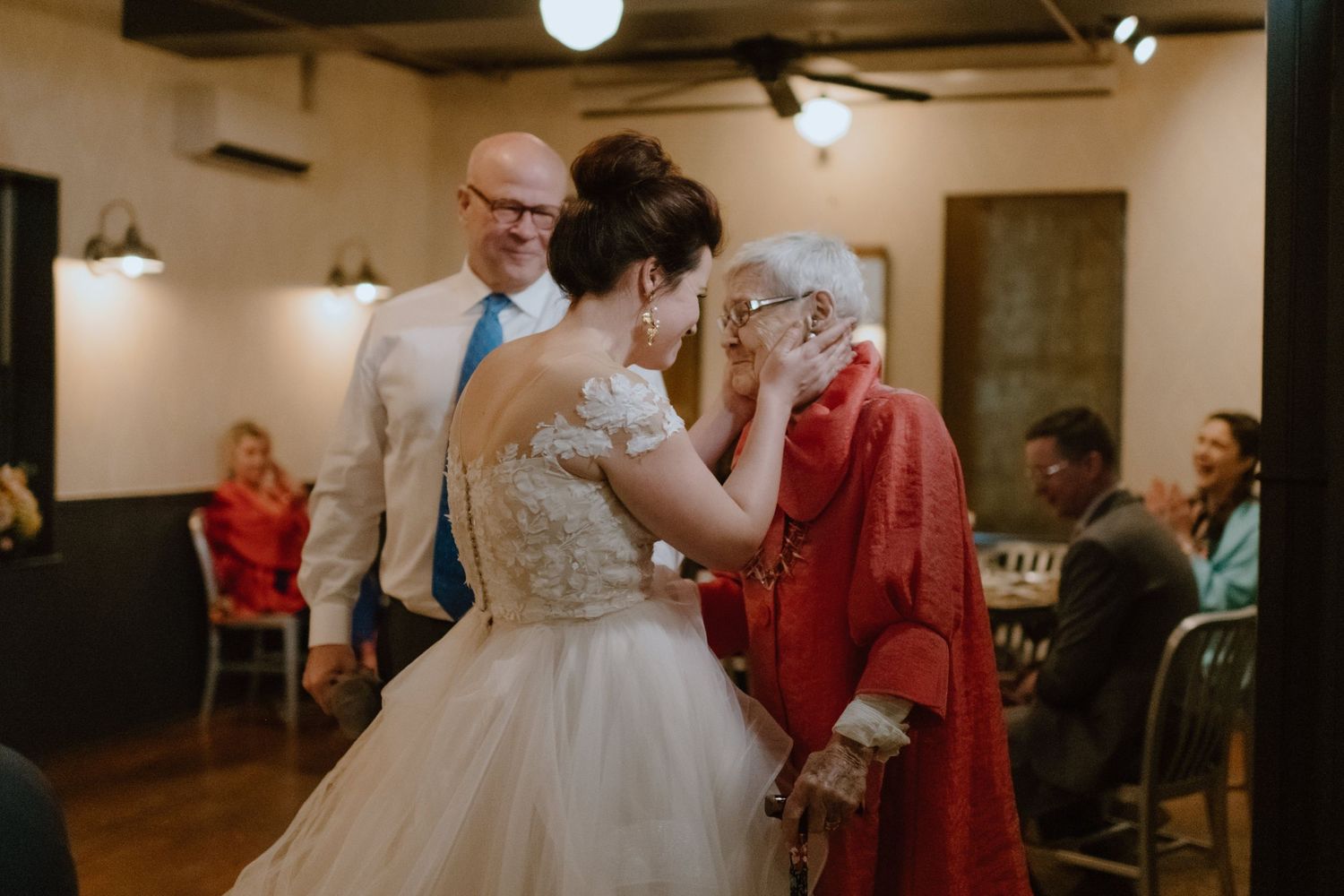 Wedding celebration in an indoor venue with guests and elegant decor.