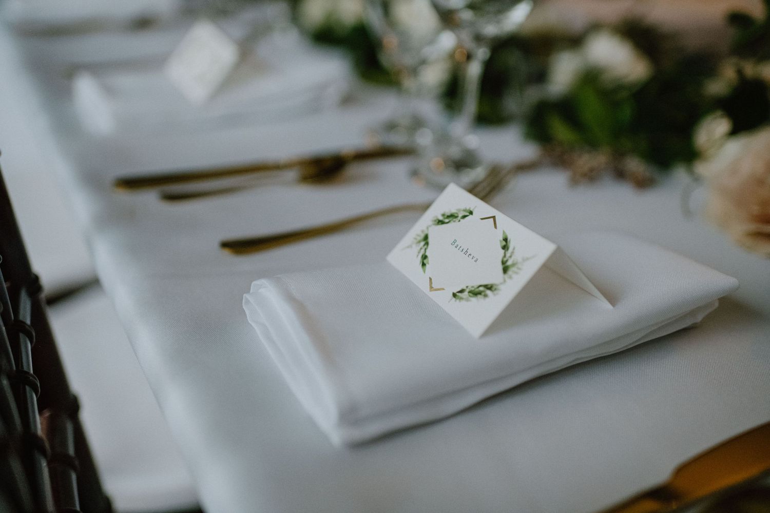 An elegant white place setting with a delicate name card and floral design.
