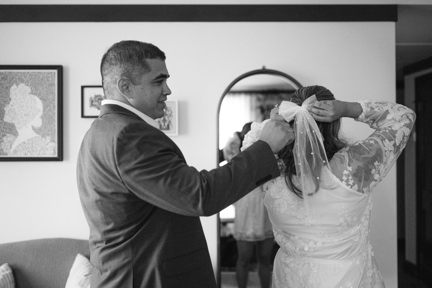 A moment of preparation as someone helps adjust a veil in black and white.