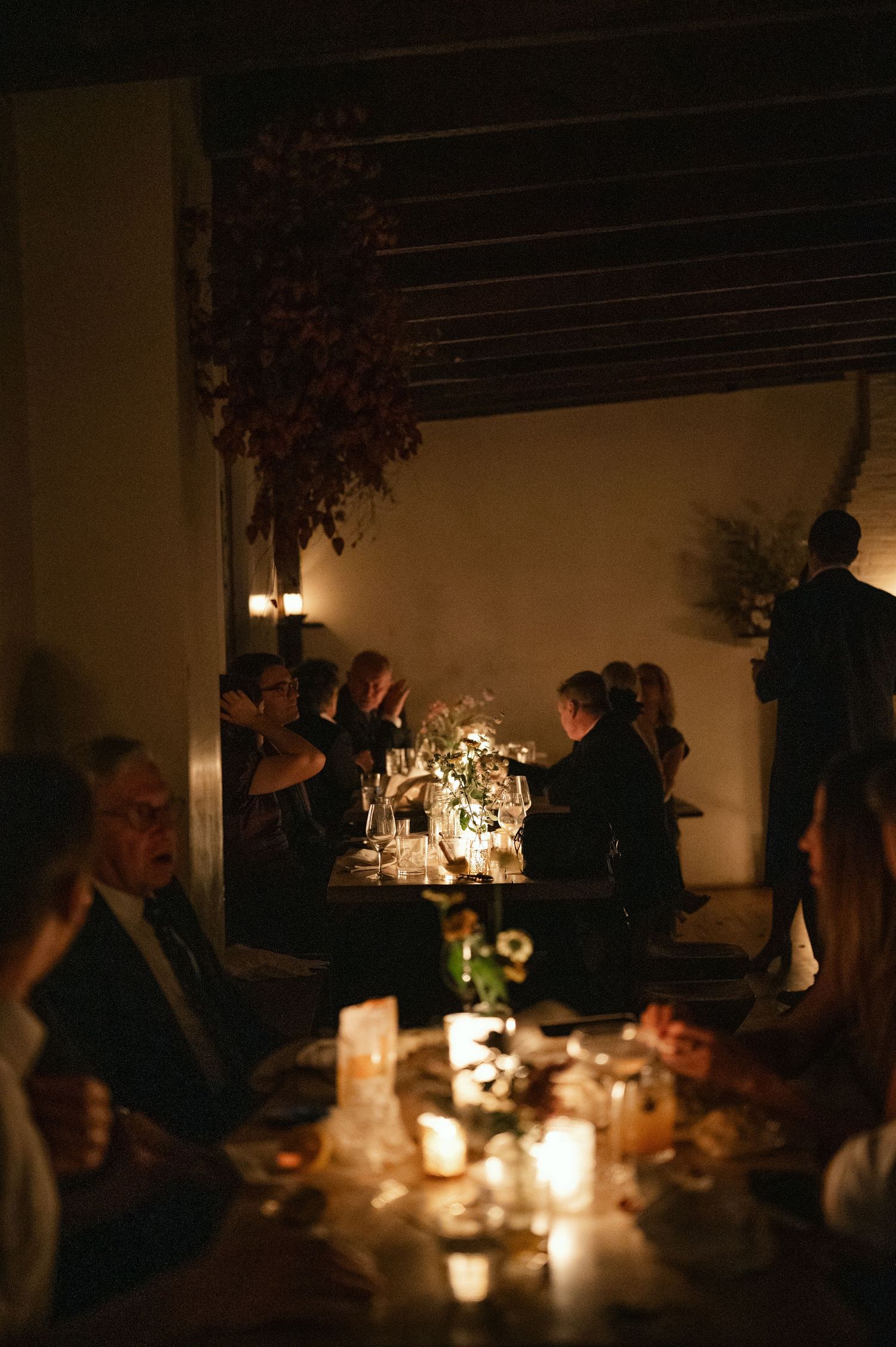 Candlelit dinner table setting creates an intimate ambiance with glowing lights and silhouettes in a dimly lit room.