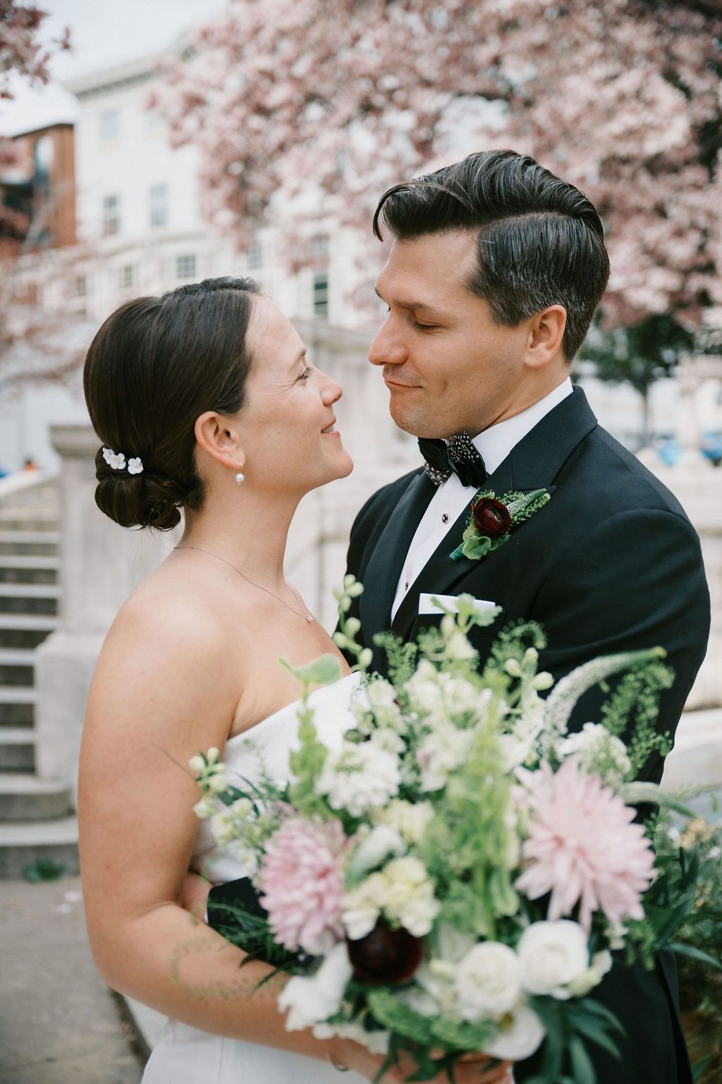 Wedding couple shares intimate moment with spring cherry blossoms in background.